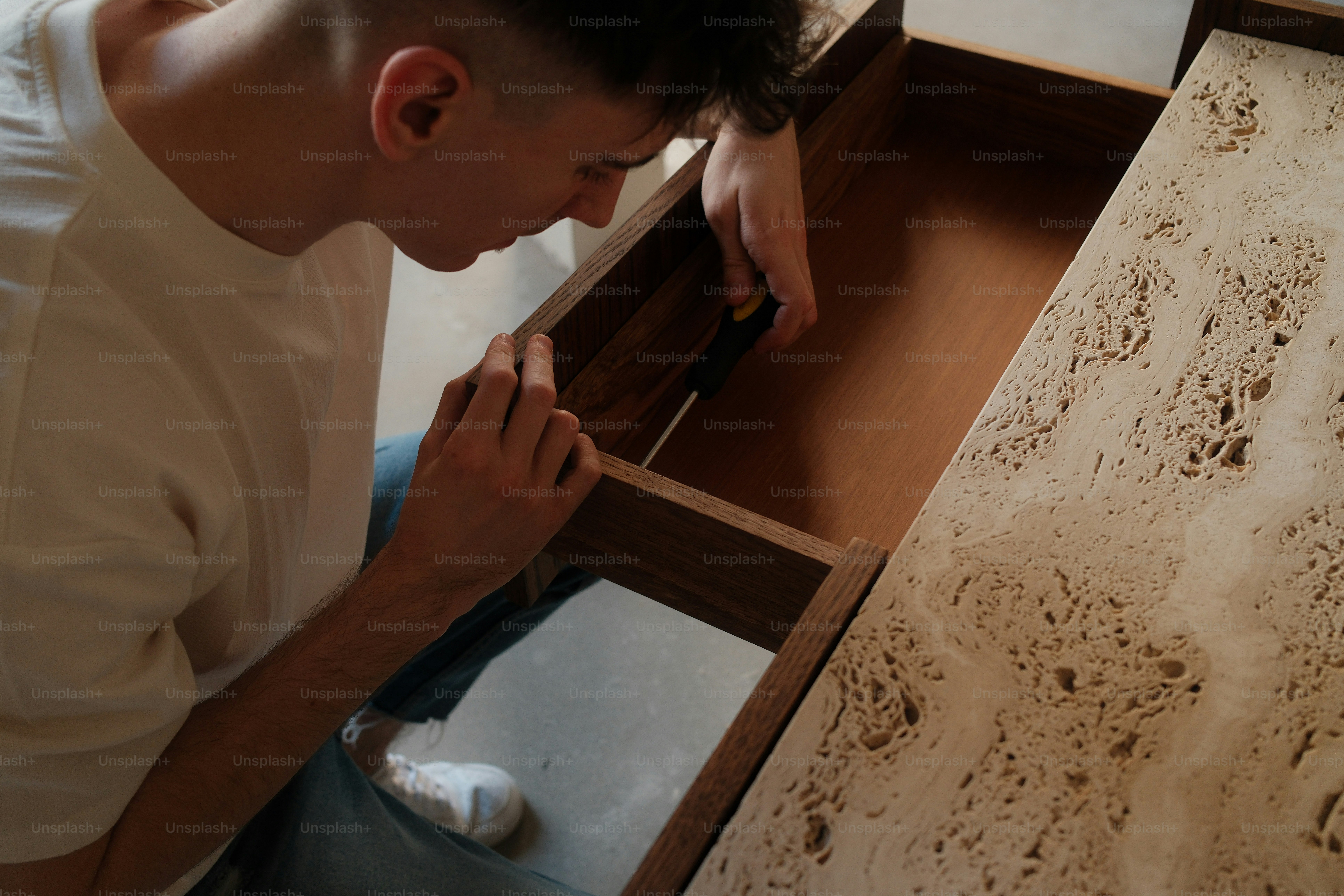 A man is assembling a wooden drawer.