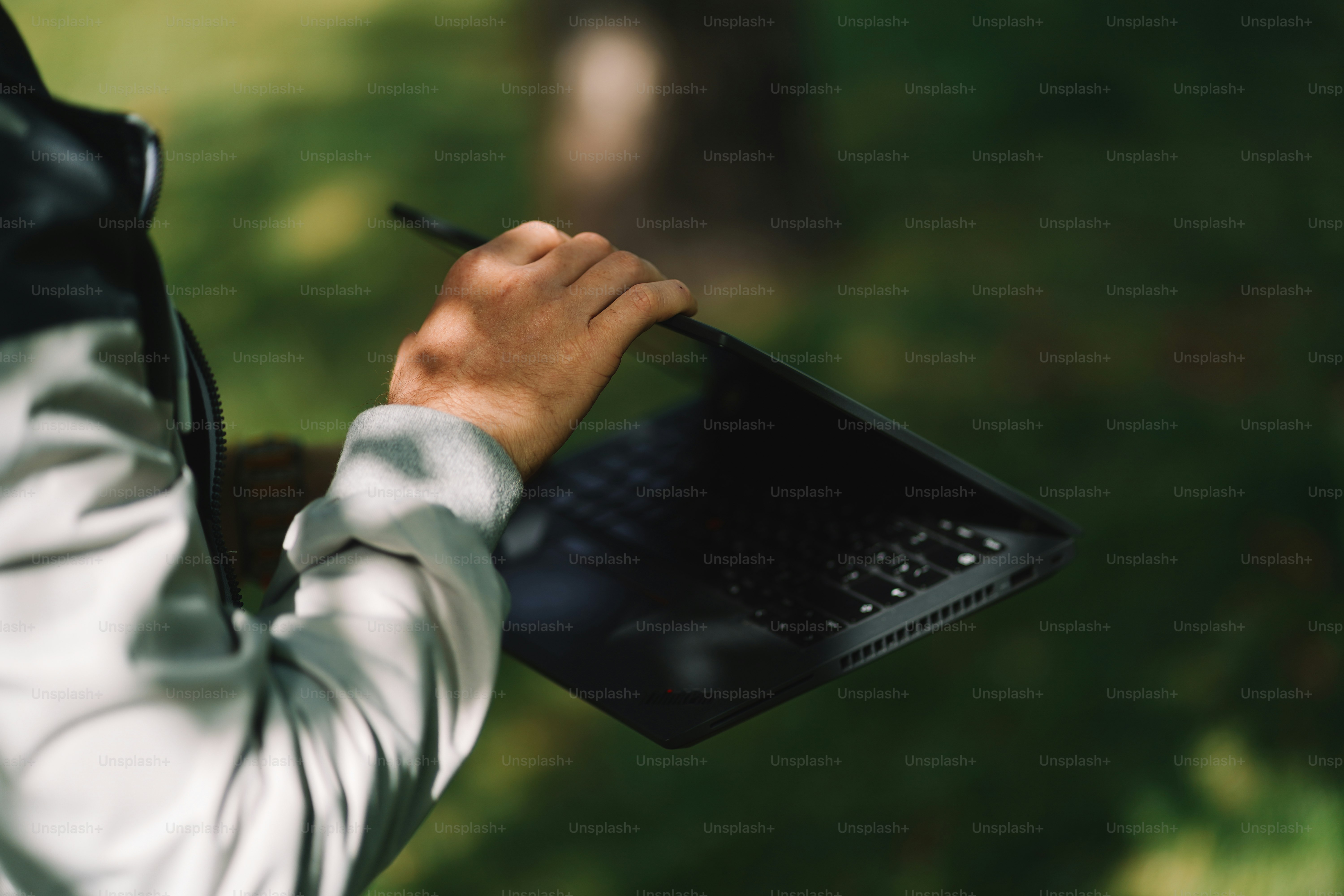 Someone is holding a laptop outdoors in the nature.