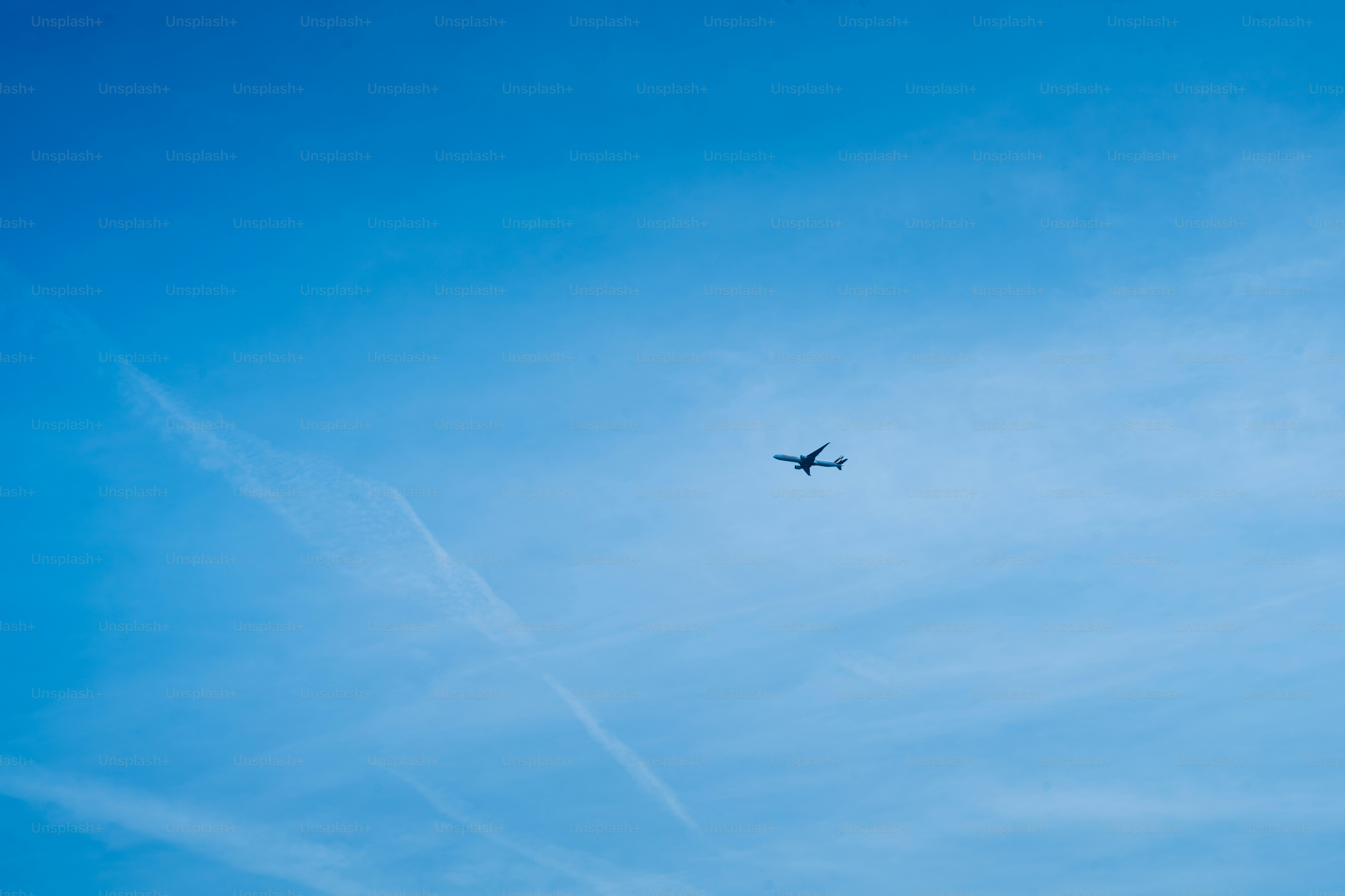 A plane flies high in a blue sky.