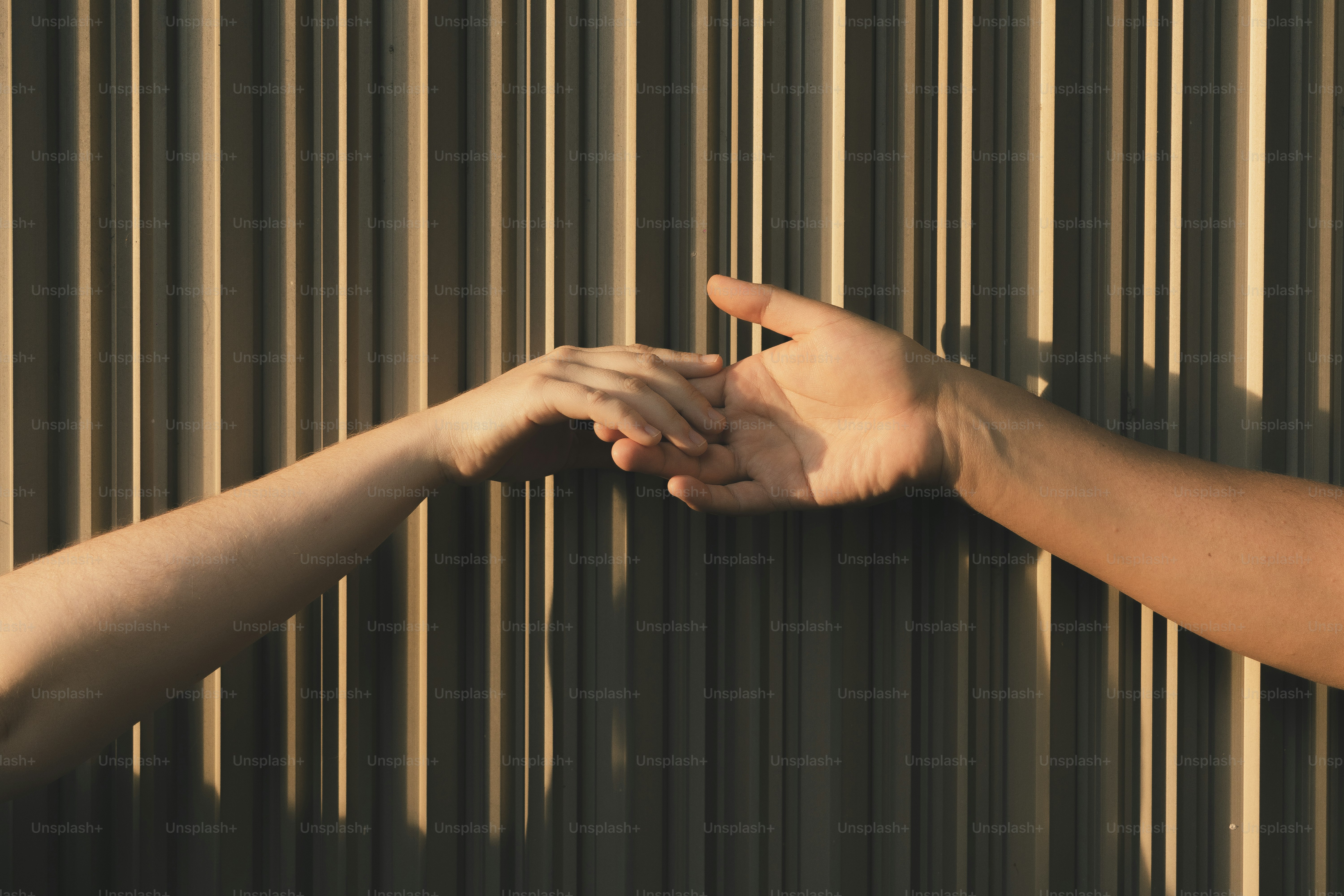 Hands reach out to touch against a striped background.