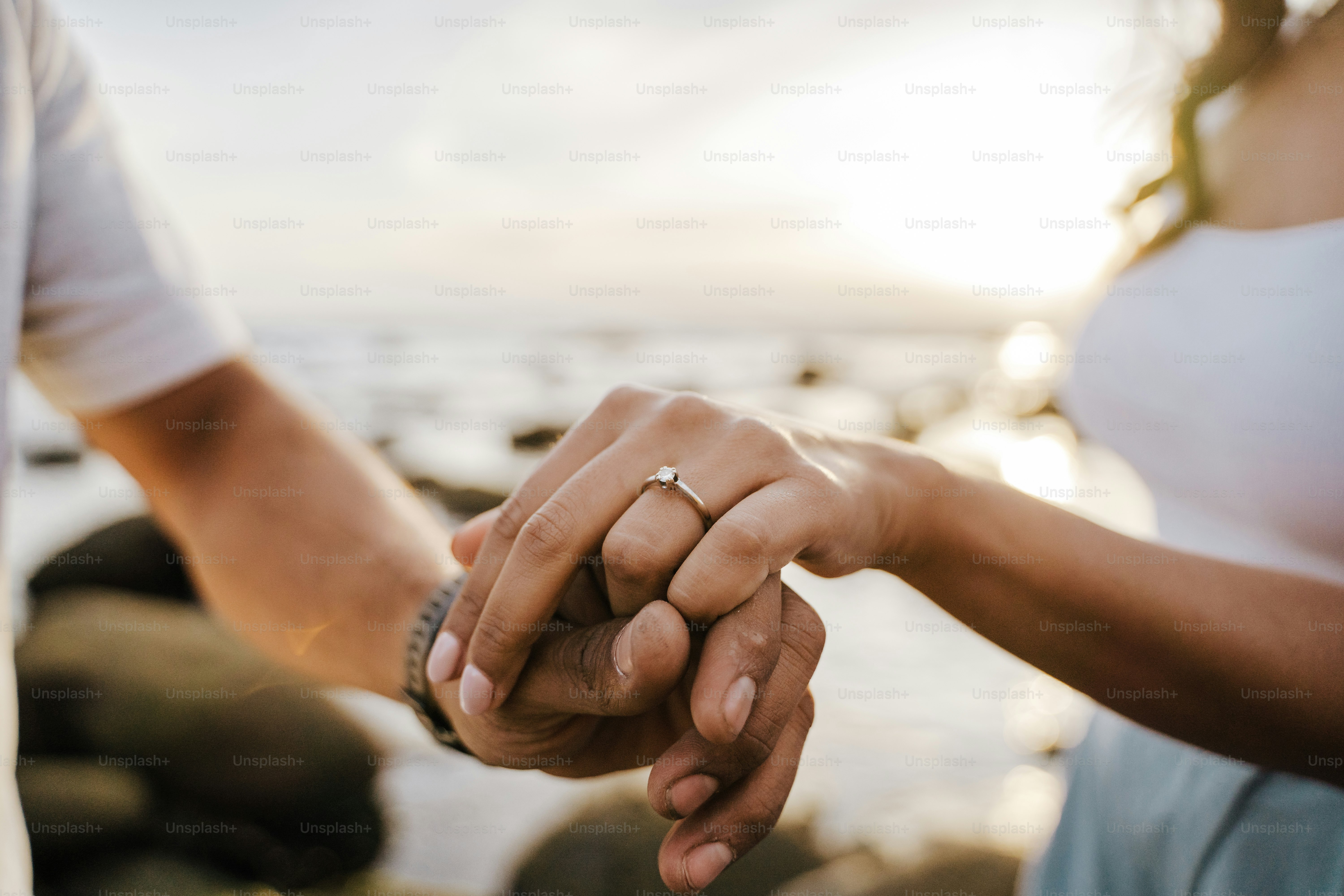 A couple holds hands with an engagement ring.