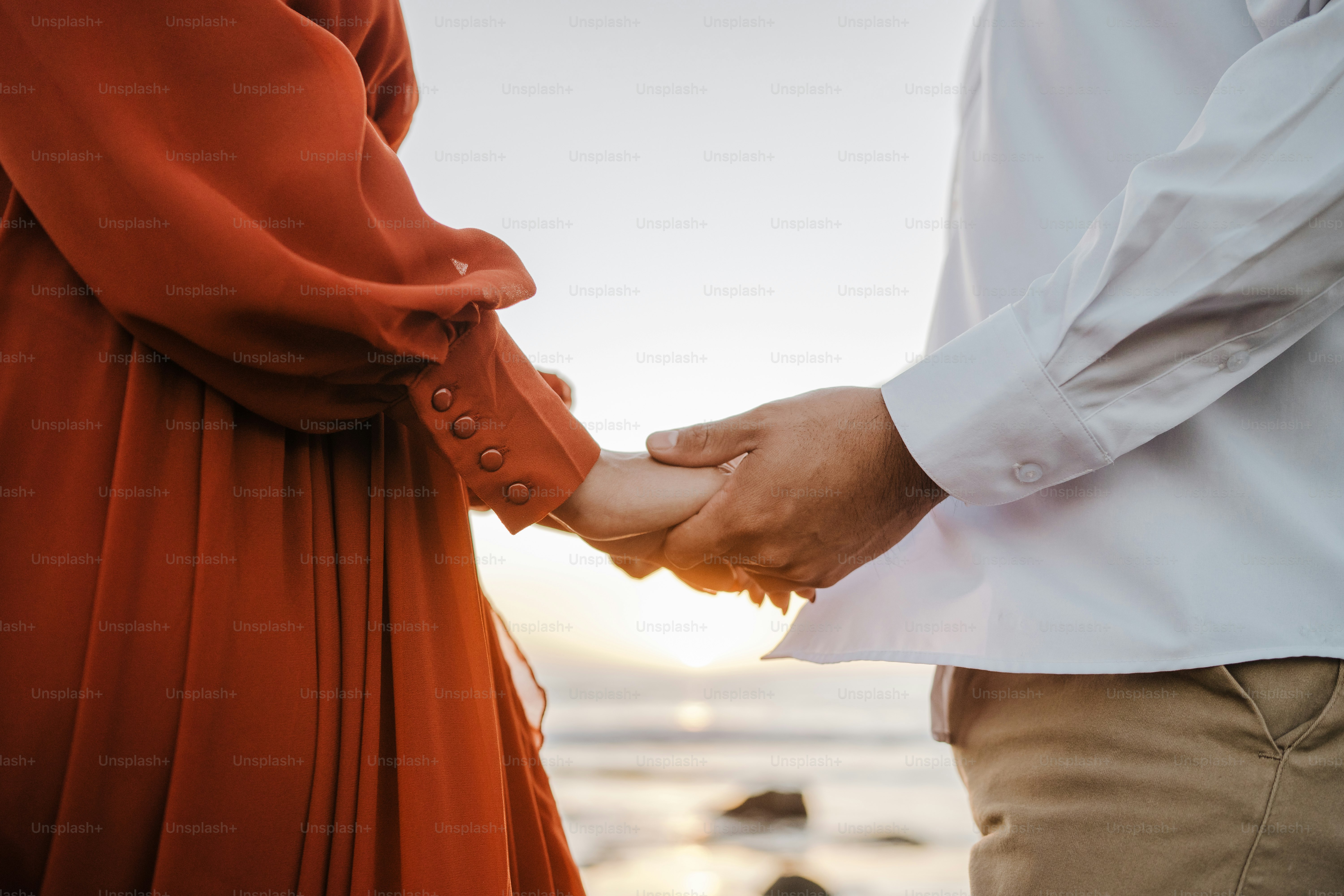 A couple holds hands at sunset.