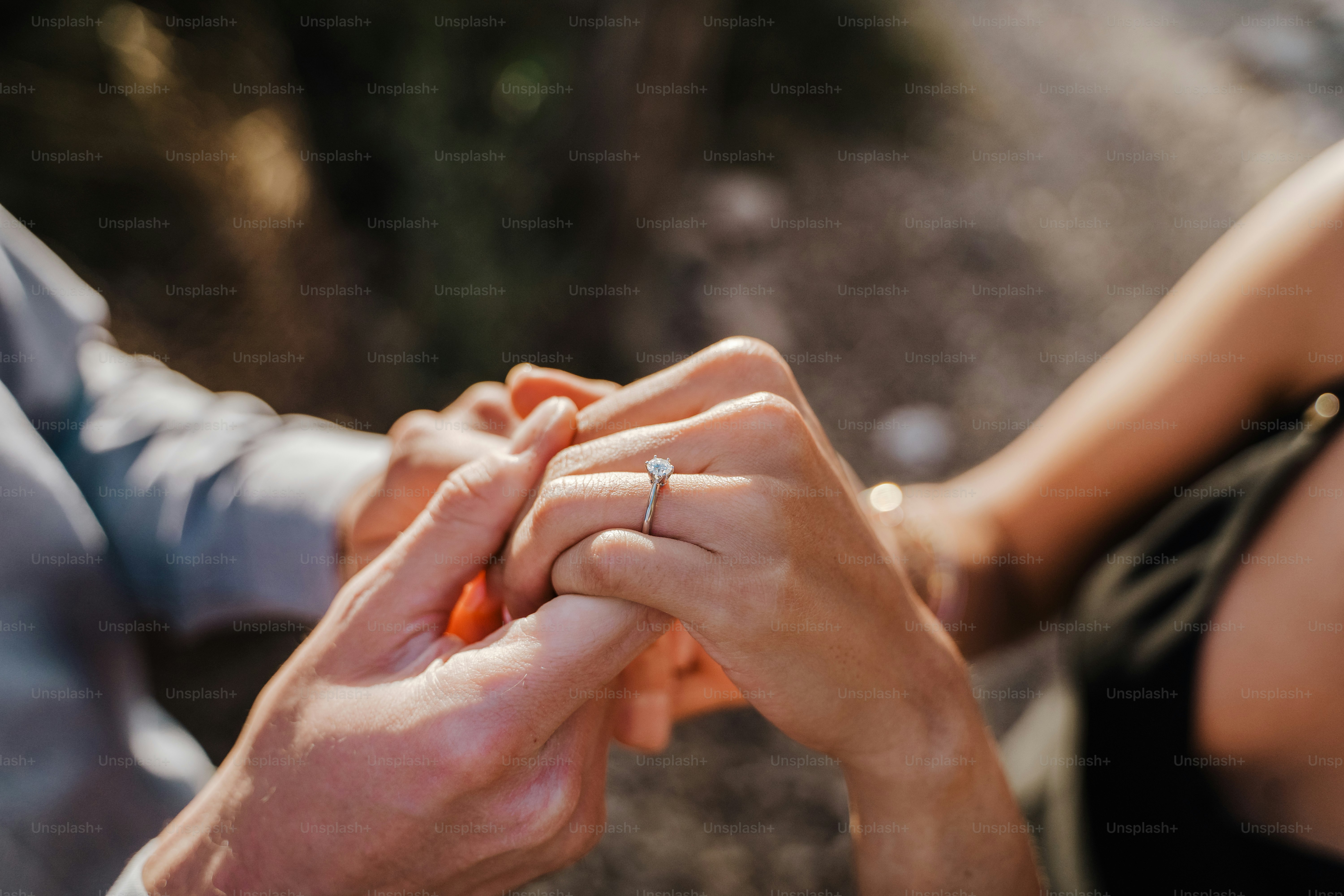 Hands clasped together, one with a sparkling engagement ring.