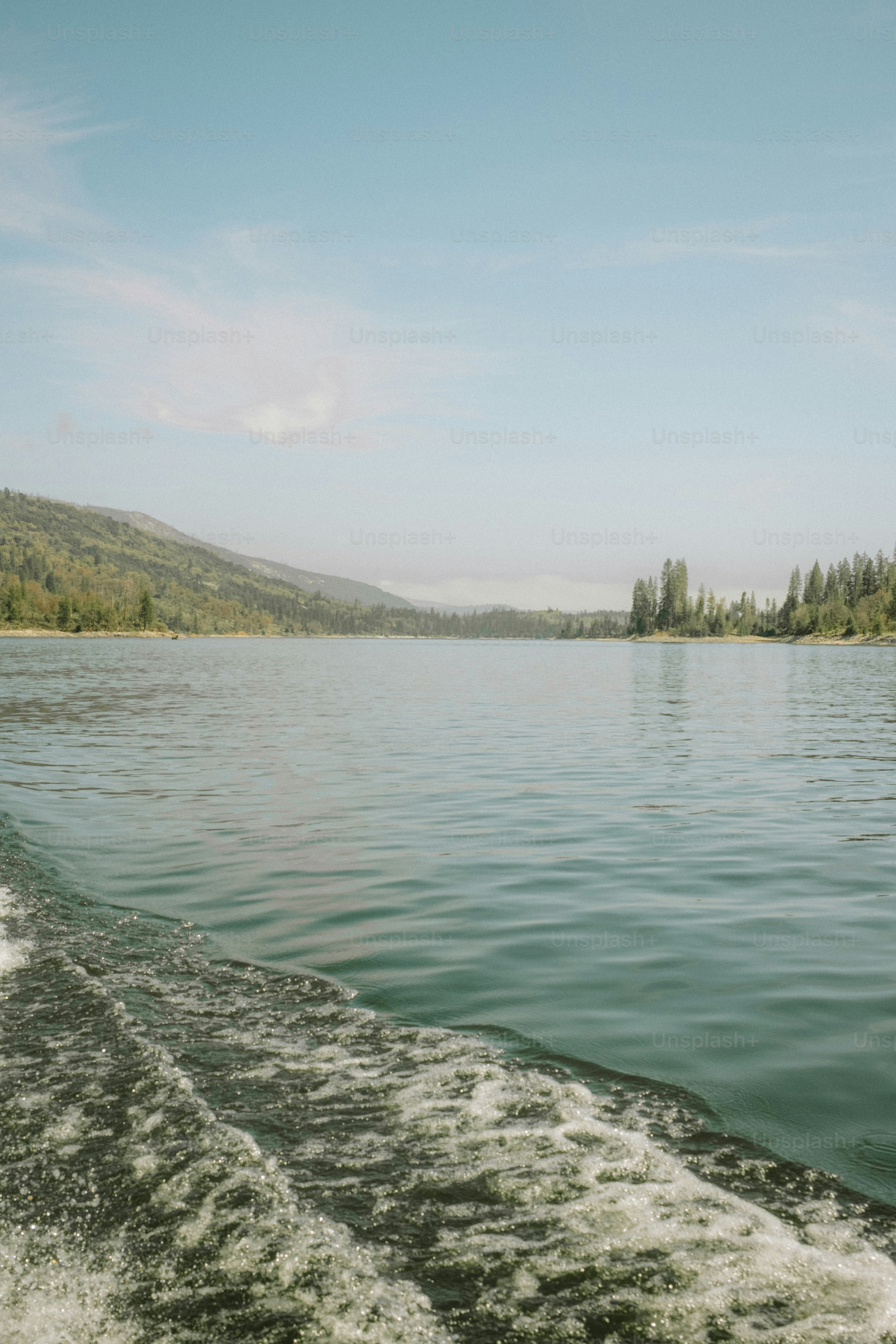 A boat travels on calm water near mountains.