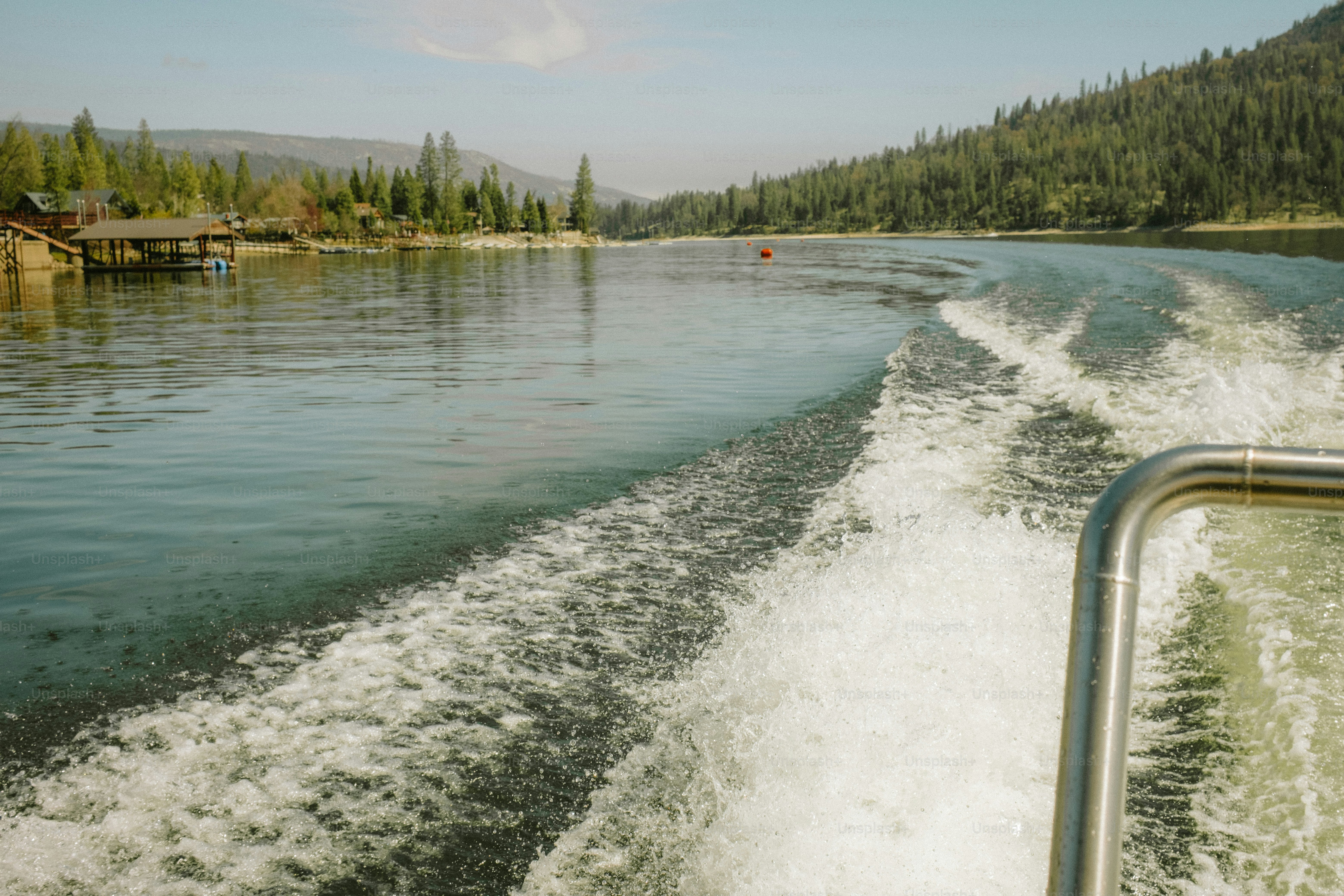 山を背景にした湖でボートが航跡を浮かべます。