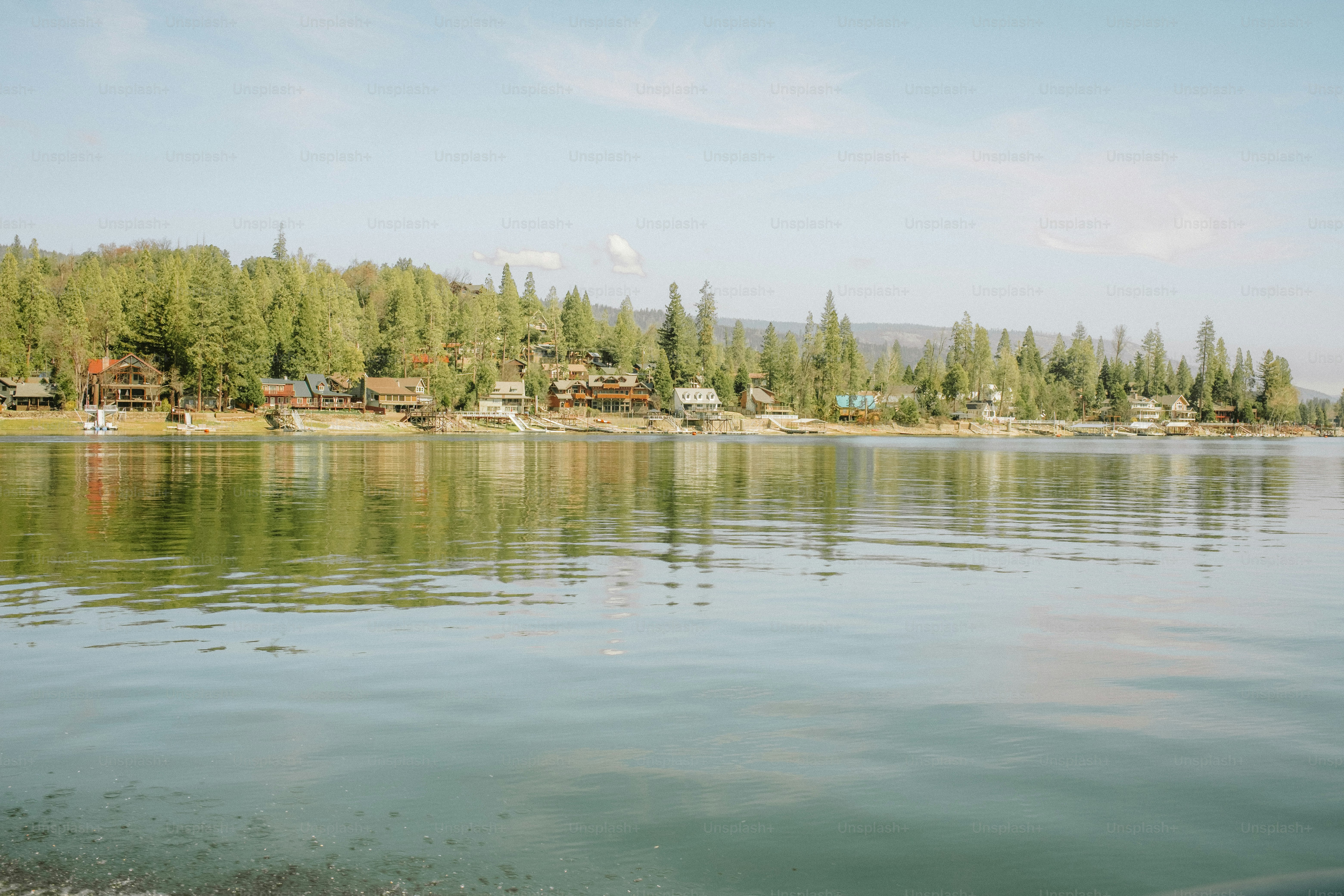 In einem ruhigen See spiegeln sich Bäume und Häuser.