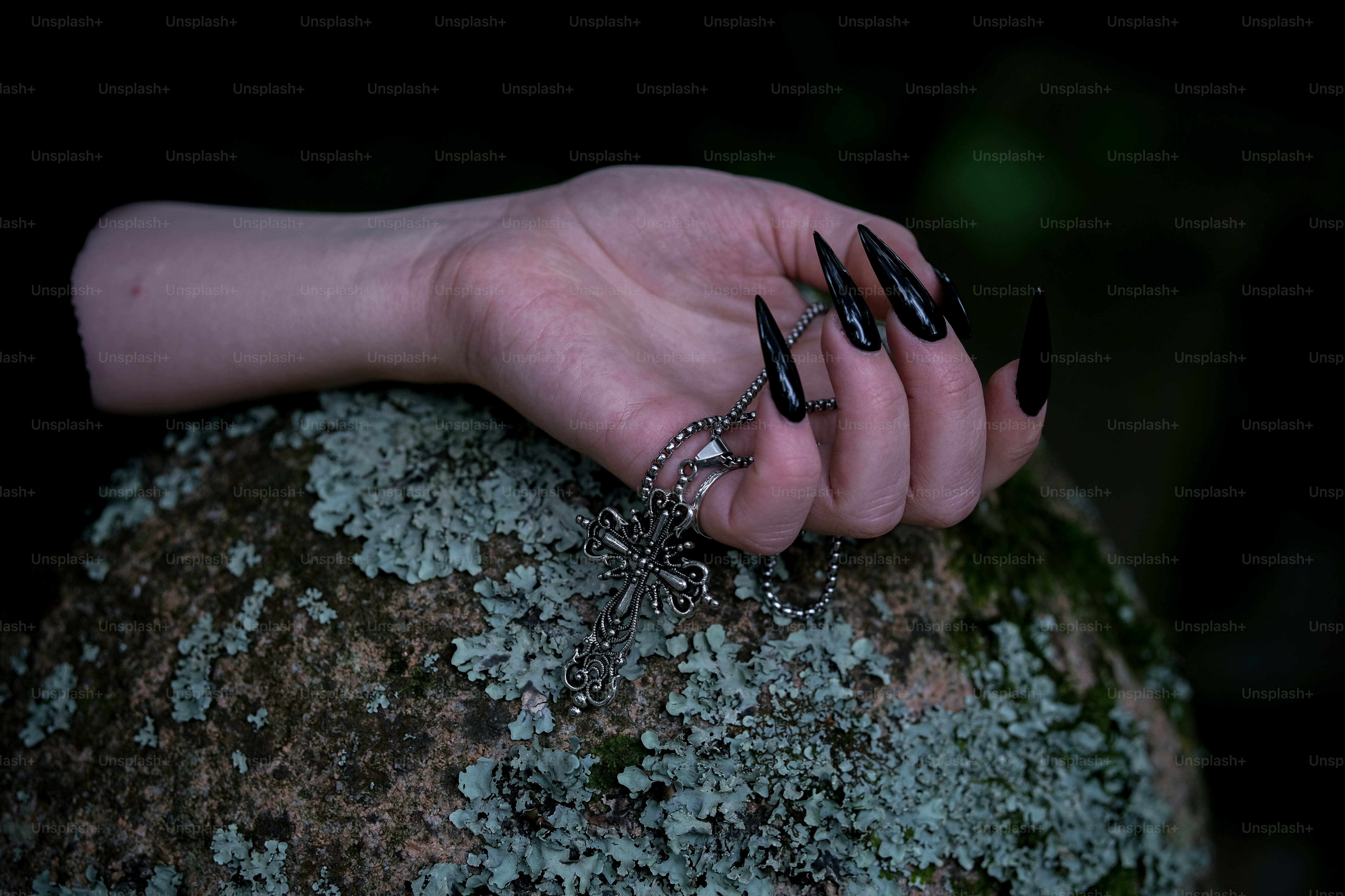 Mão com unhas pretas segura um colar.