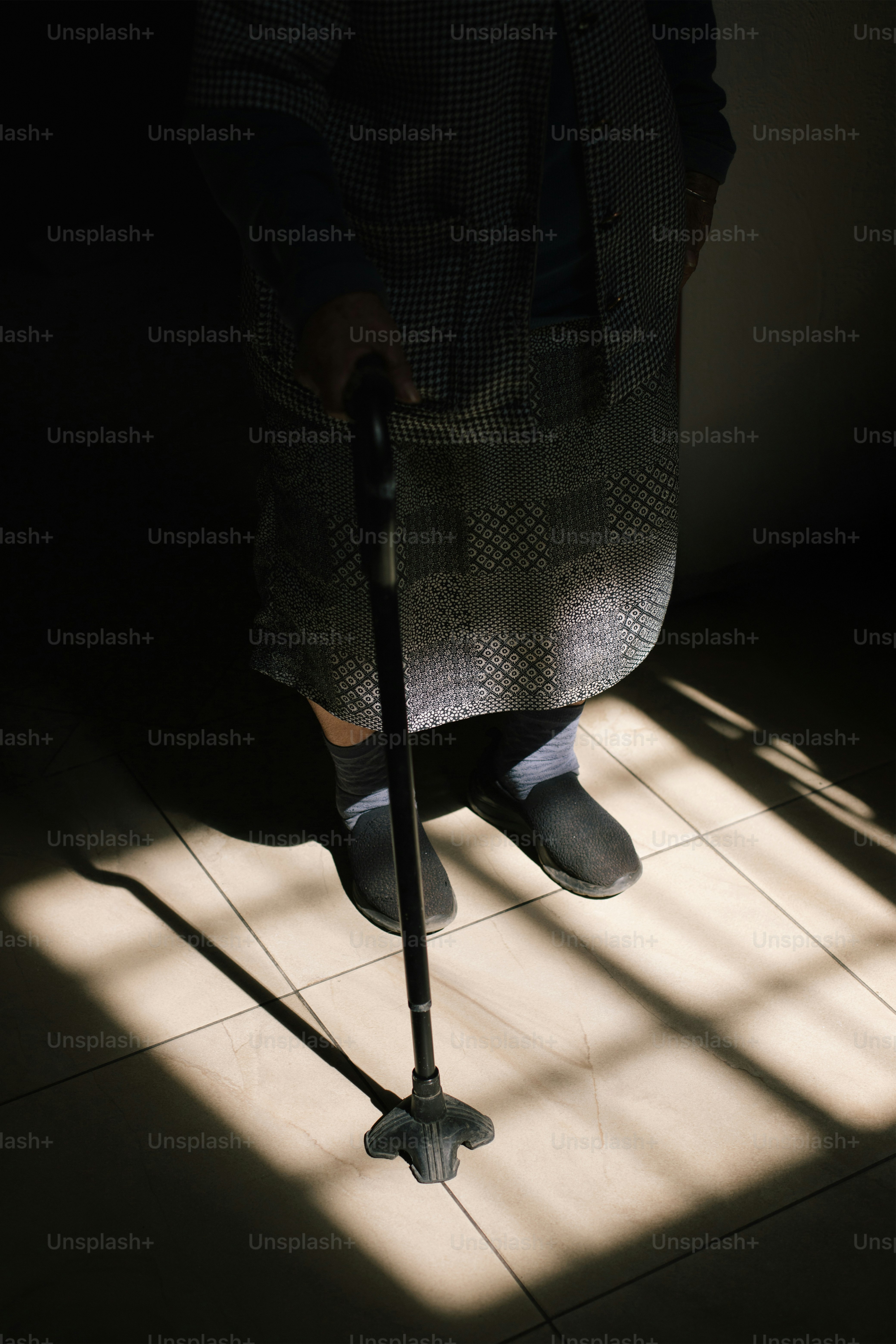 Una persona mayor está de pie con un bastón.