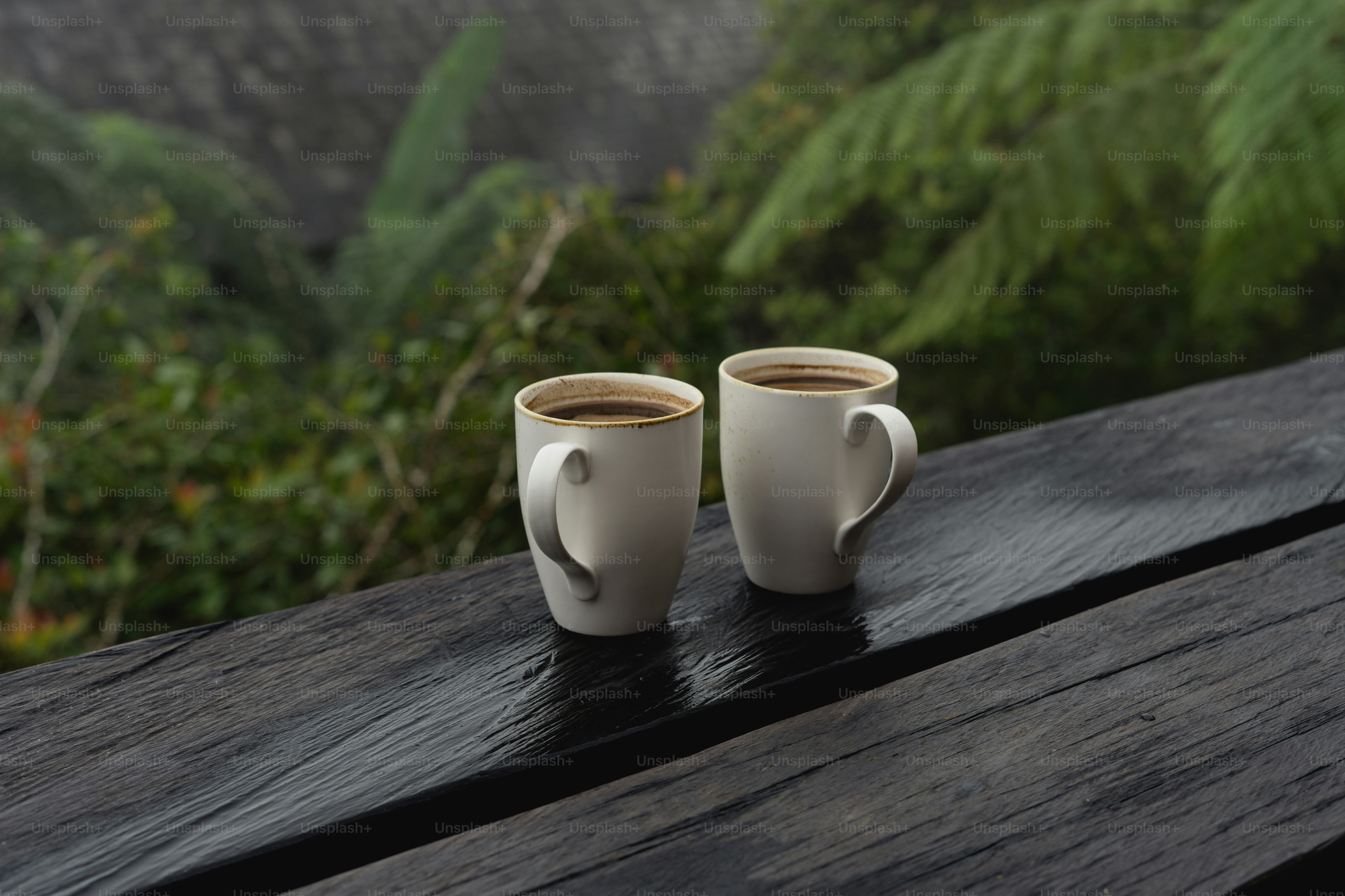 Two cups of coffee on a rustic wooden deck.
