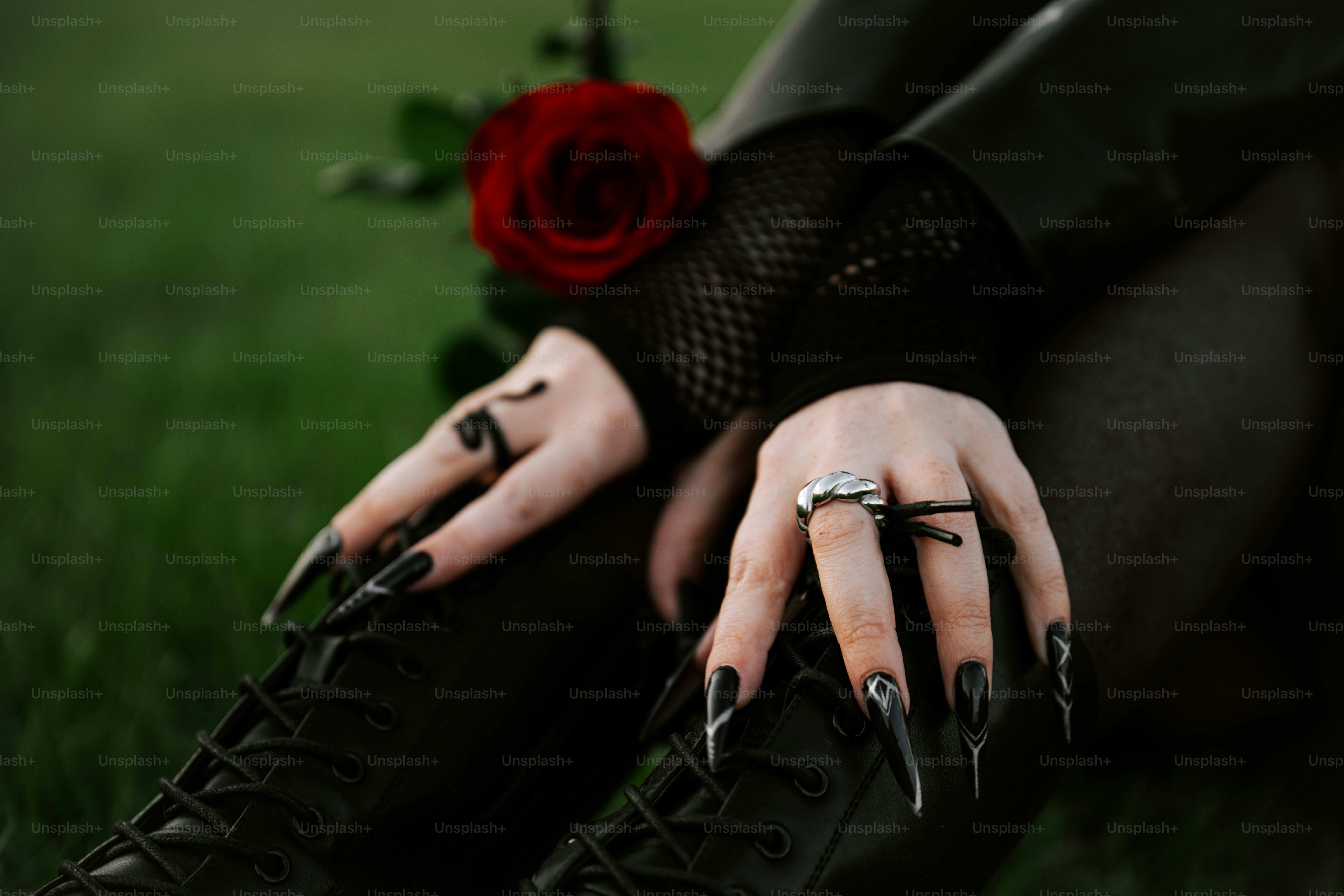 Hands with black nails and a red rose.