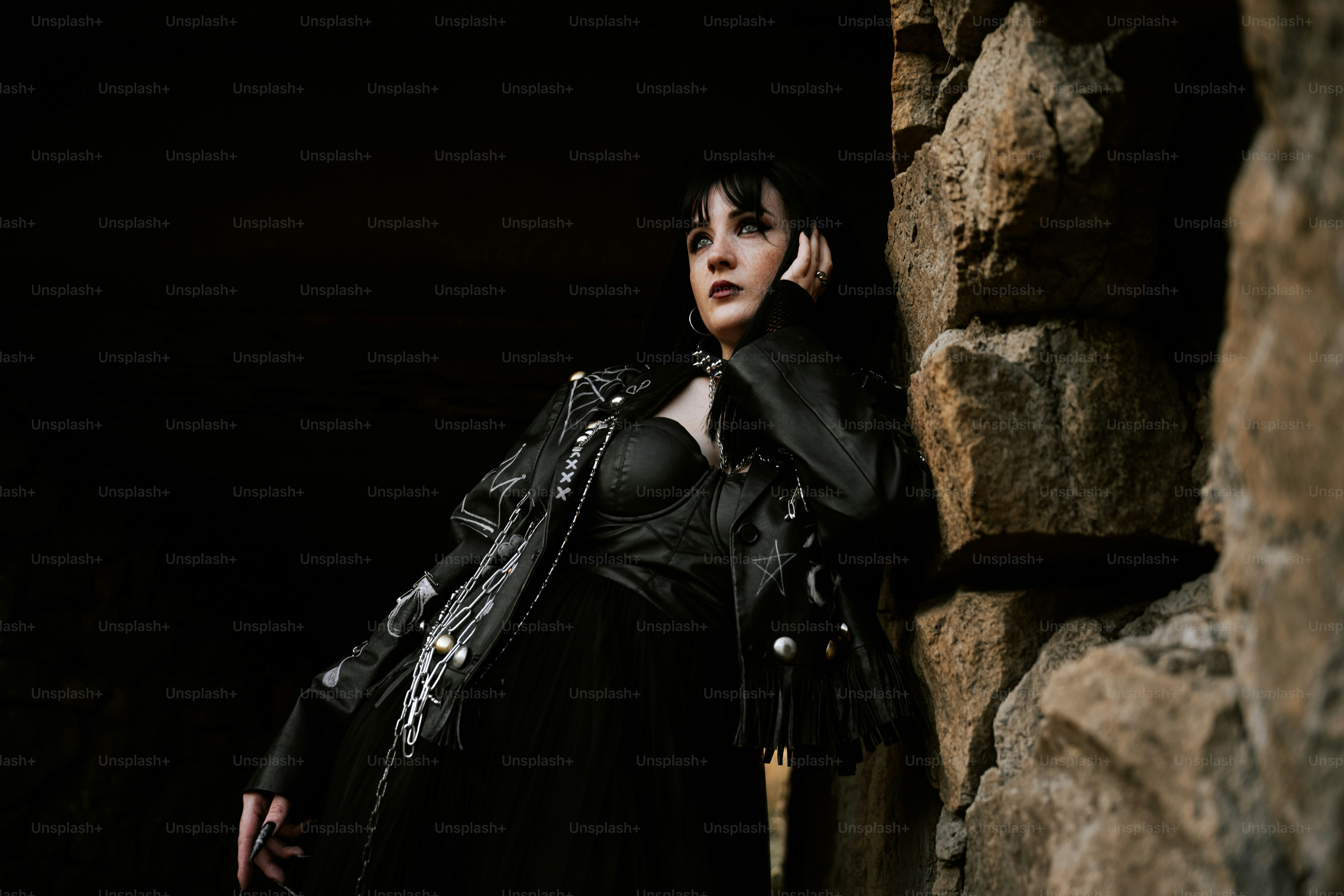 A woman poses near a stone wall.