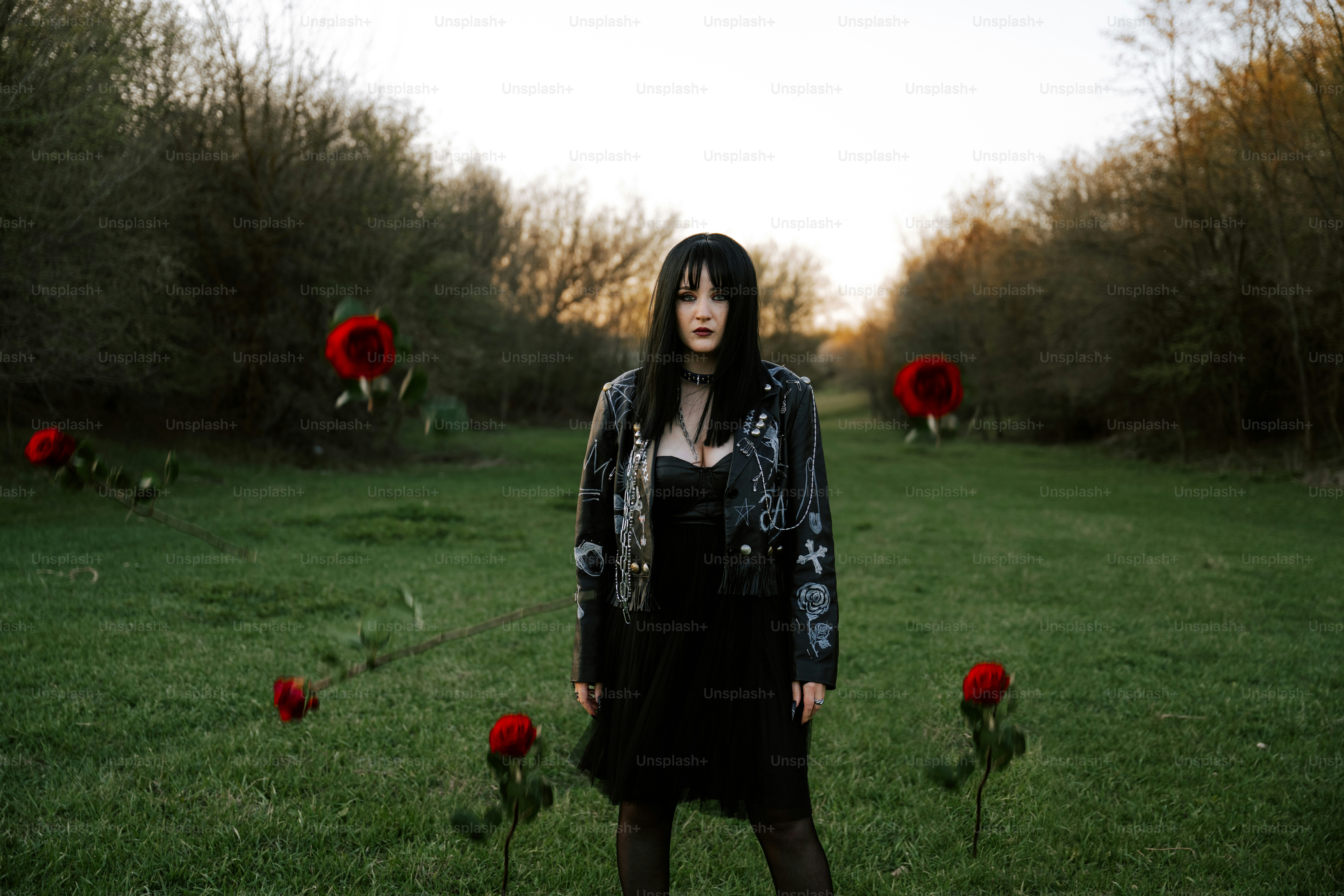 A woman stands among floating red roses.