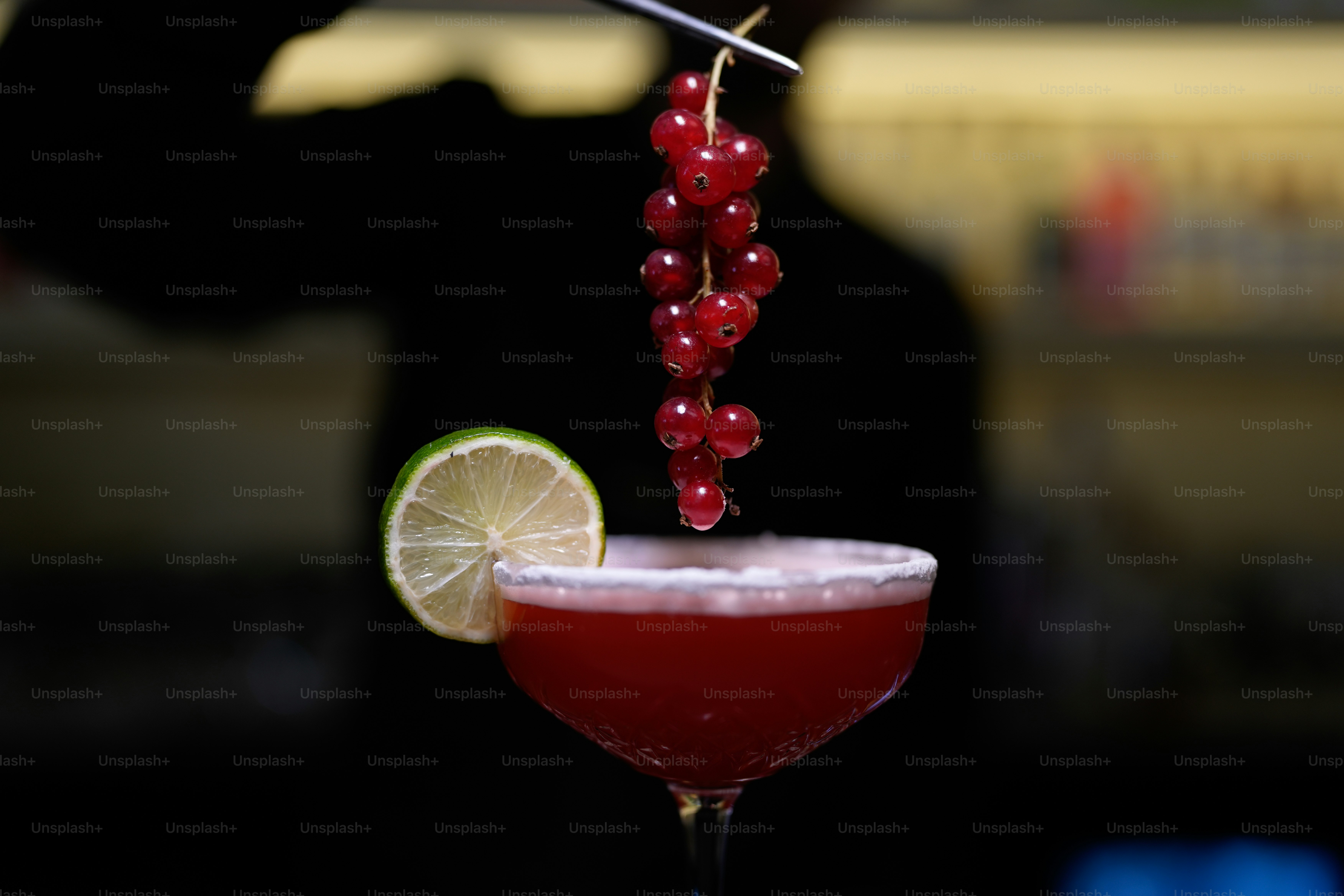 Um coquetel está sendo decorado com frutas vermelhas e limão.