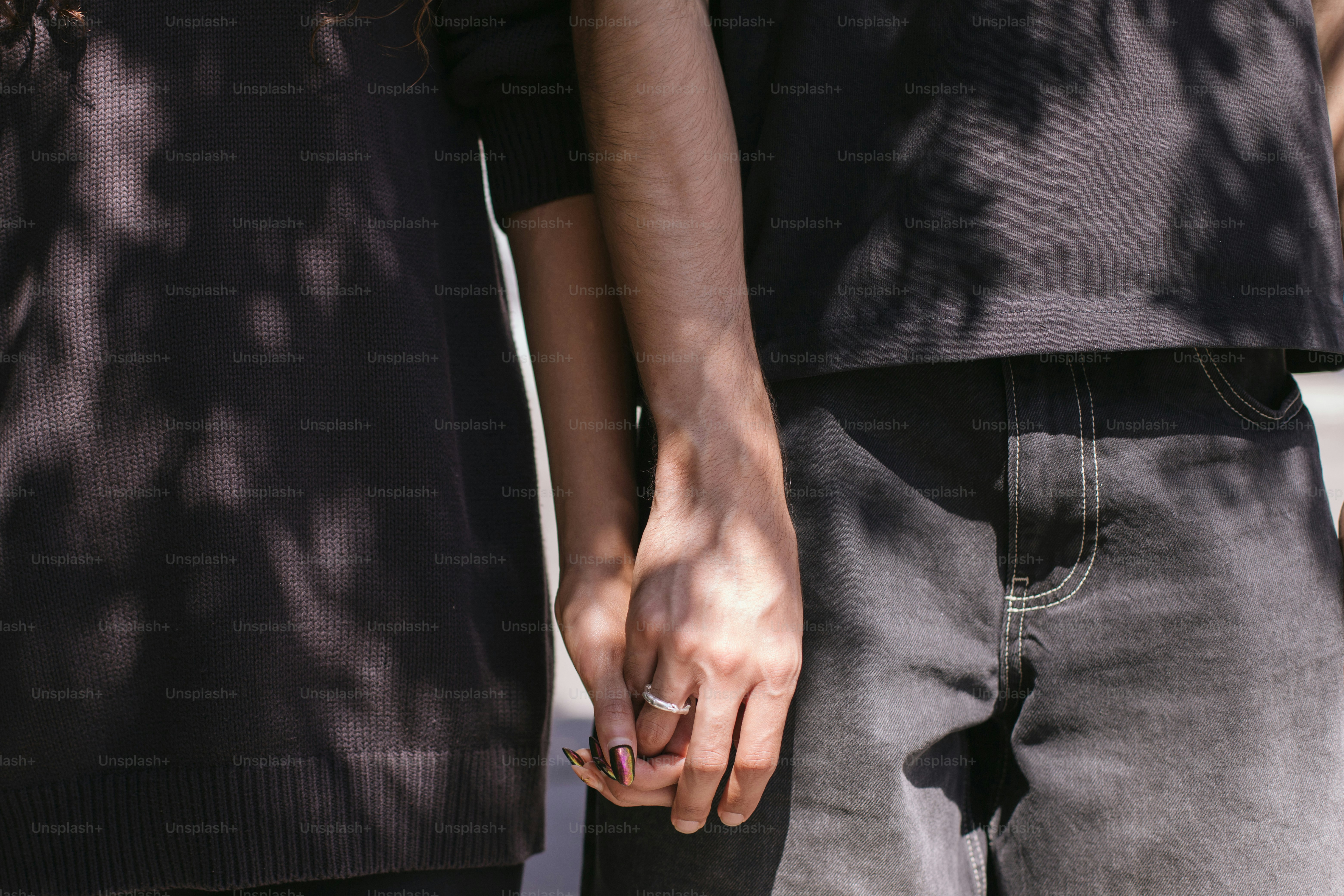 Two people hold hands, showing a ring.