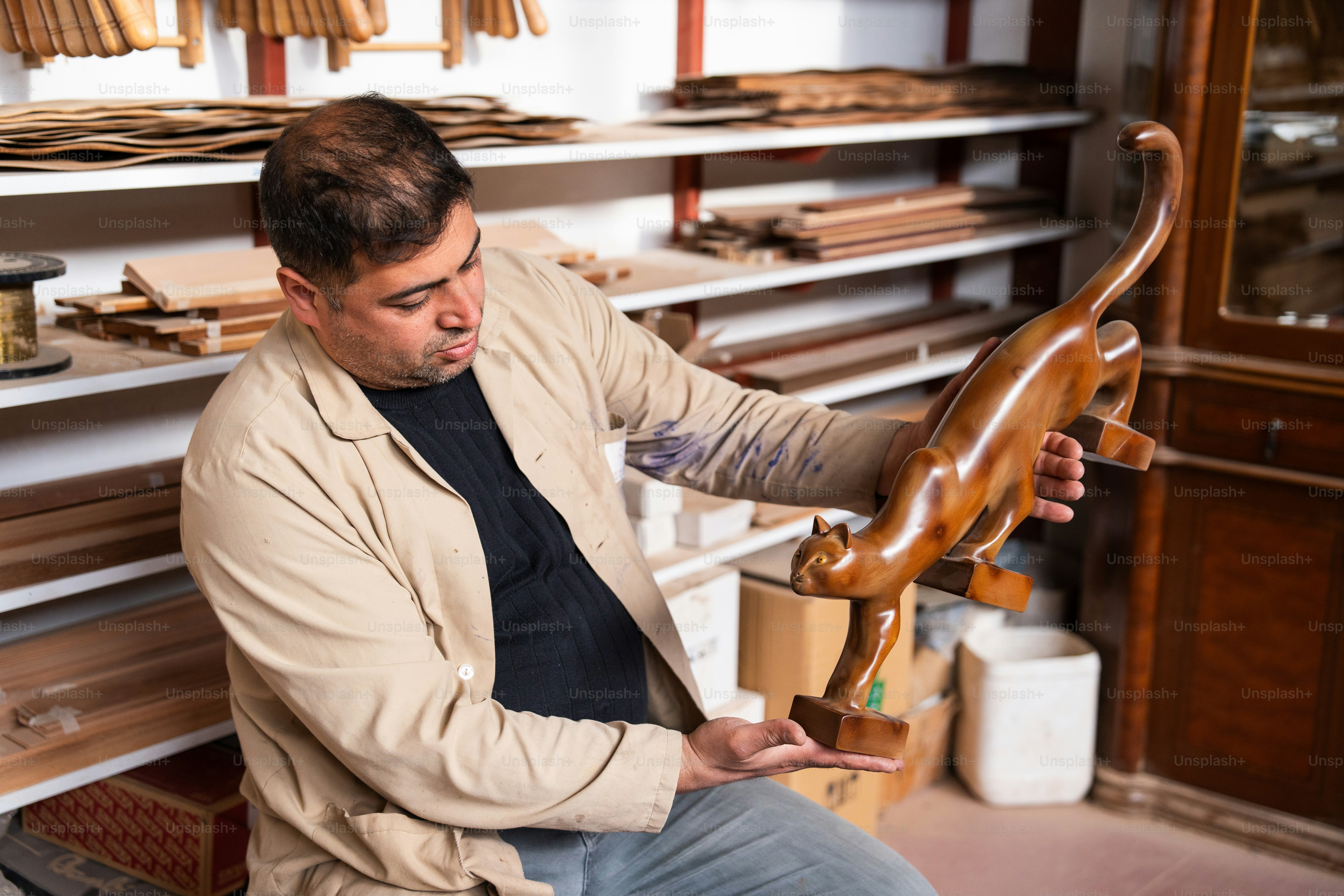 Un artesano admira una escultura de madera de un gato