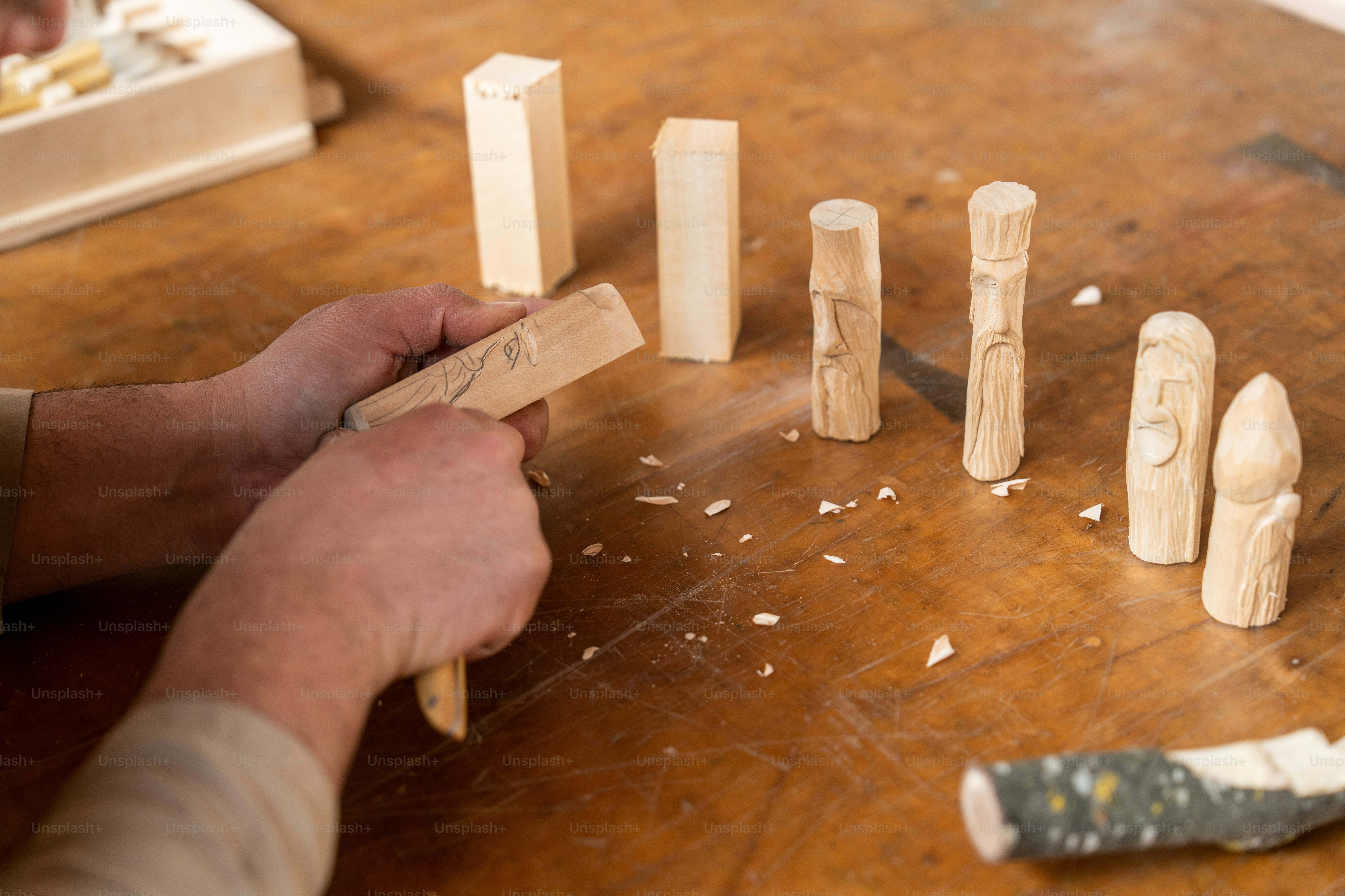 Someone is carving wooden figures on a table.