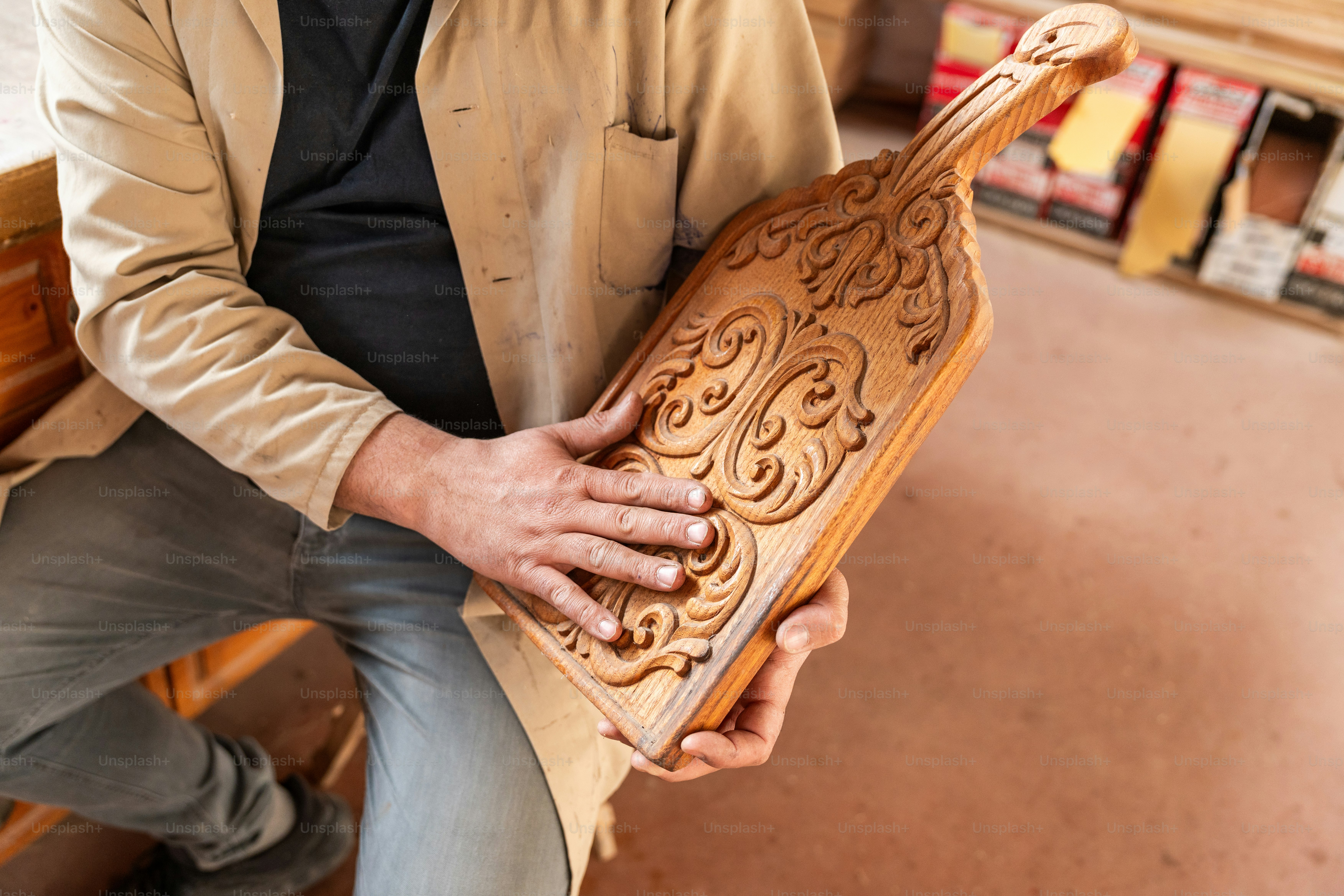 A craftsman inspects a beautifully carved wooden object.