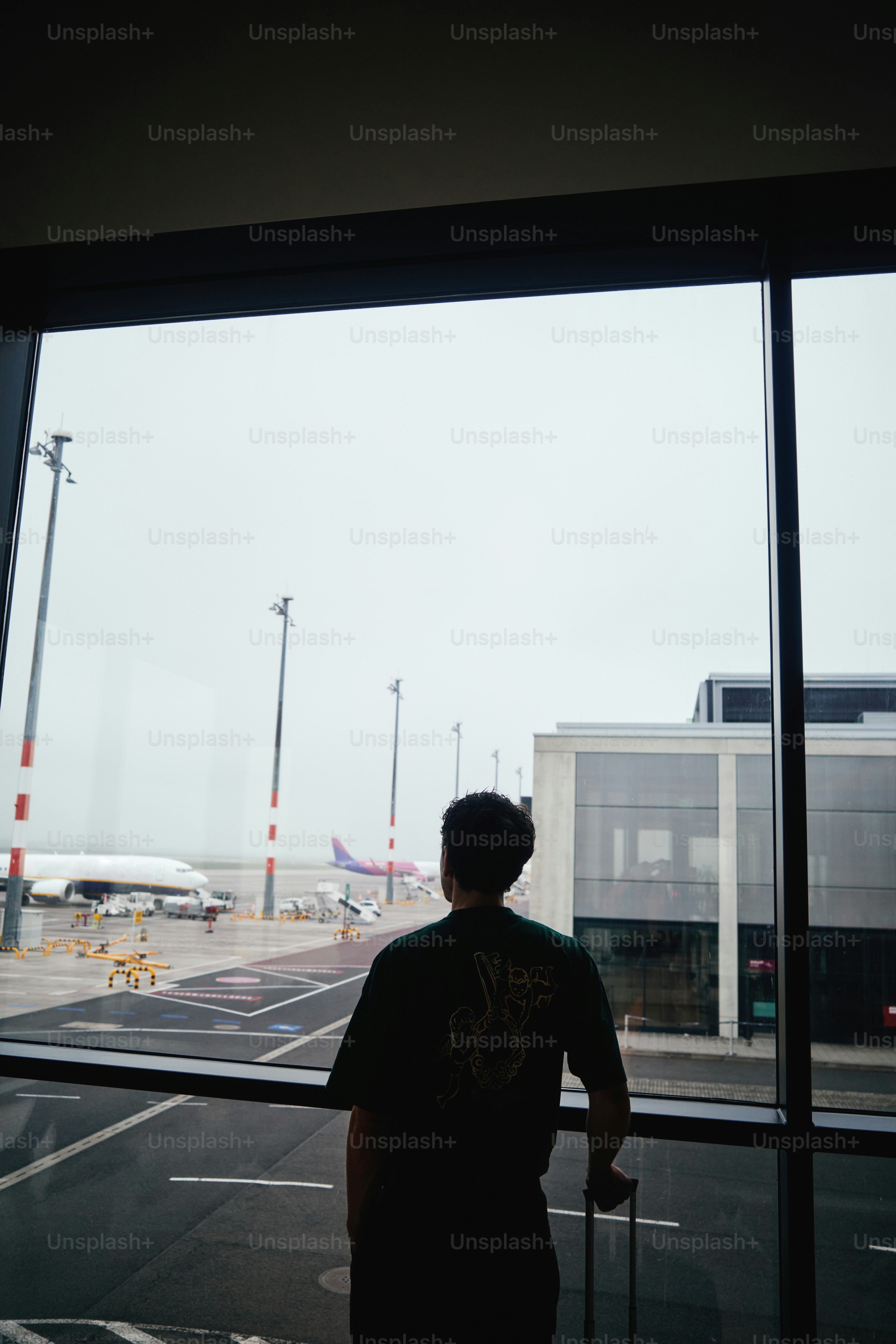 Un hombre espera en la ventana del aeropuerto, mirando los aviones.