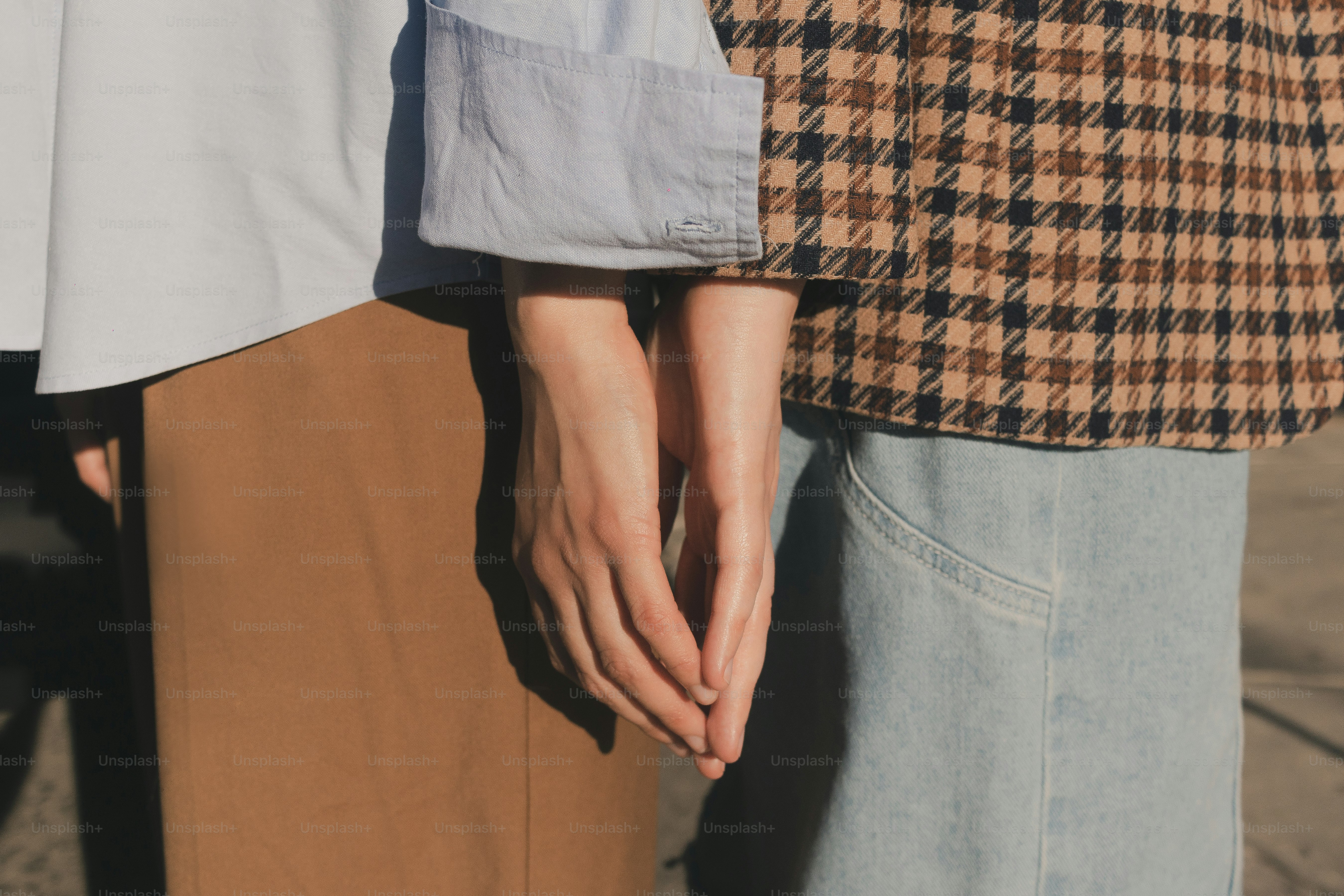 Two people are standing close, holding hands.