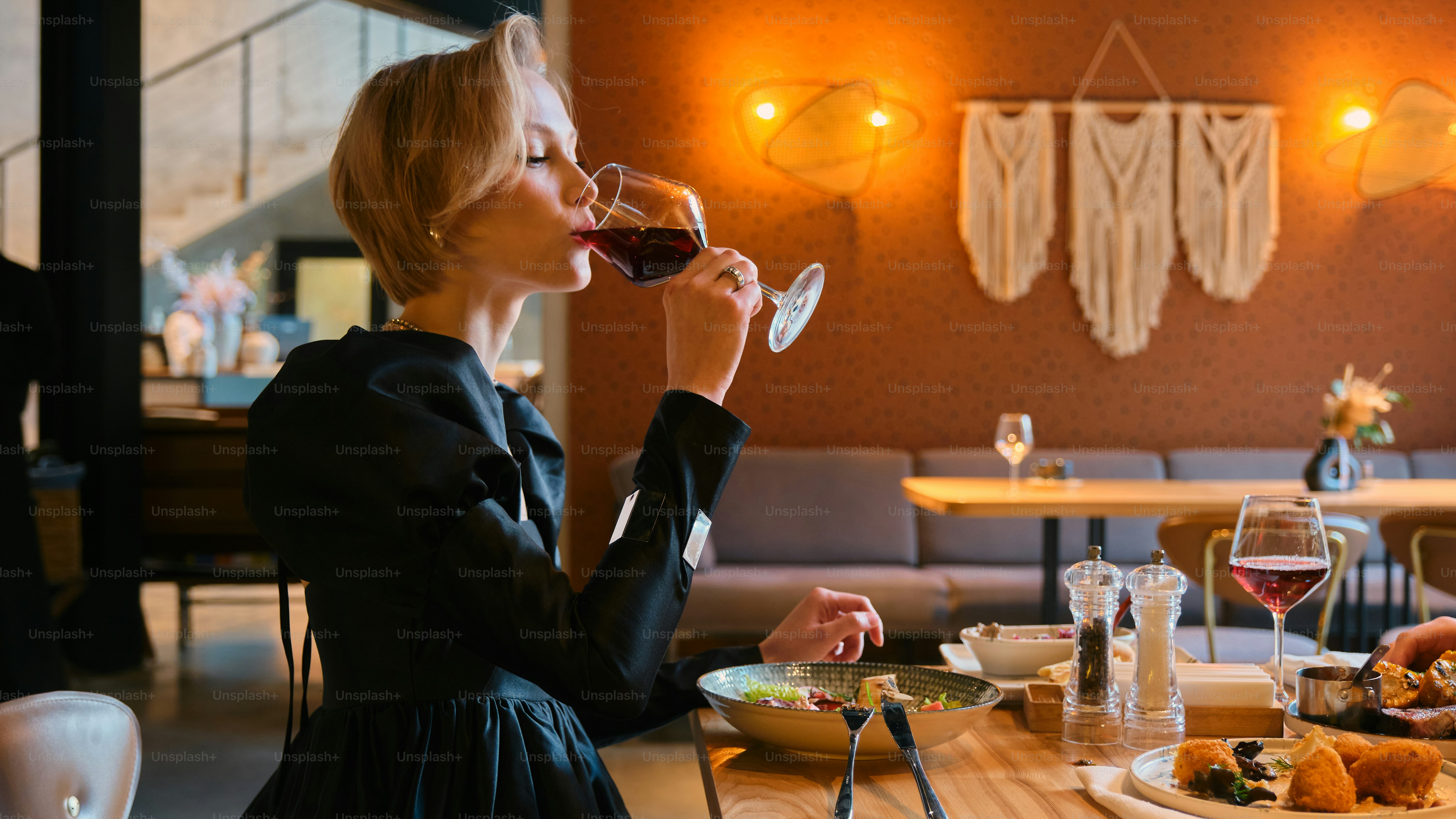 Woman sips wine at a restaurant table.