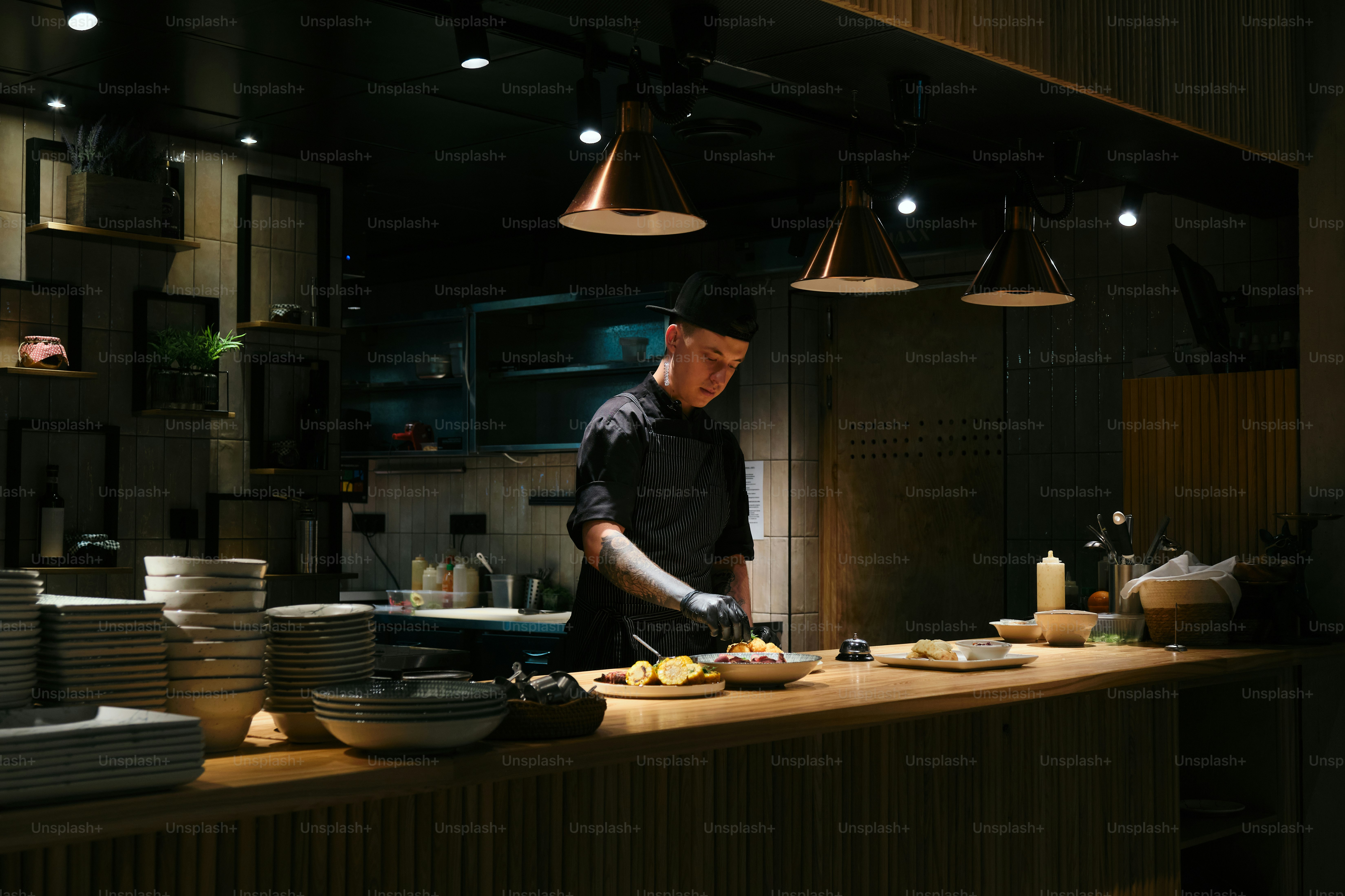Chef prepares food in a dimly lit restaurant kitchen.