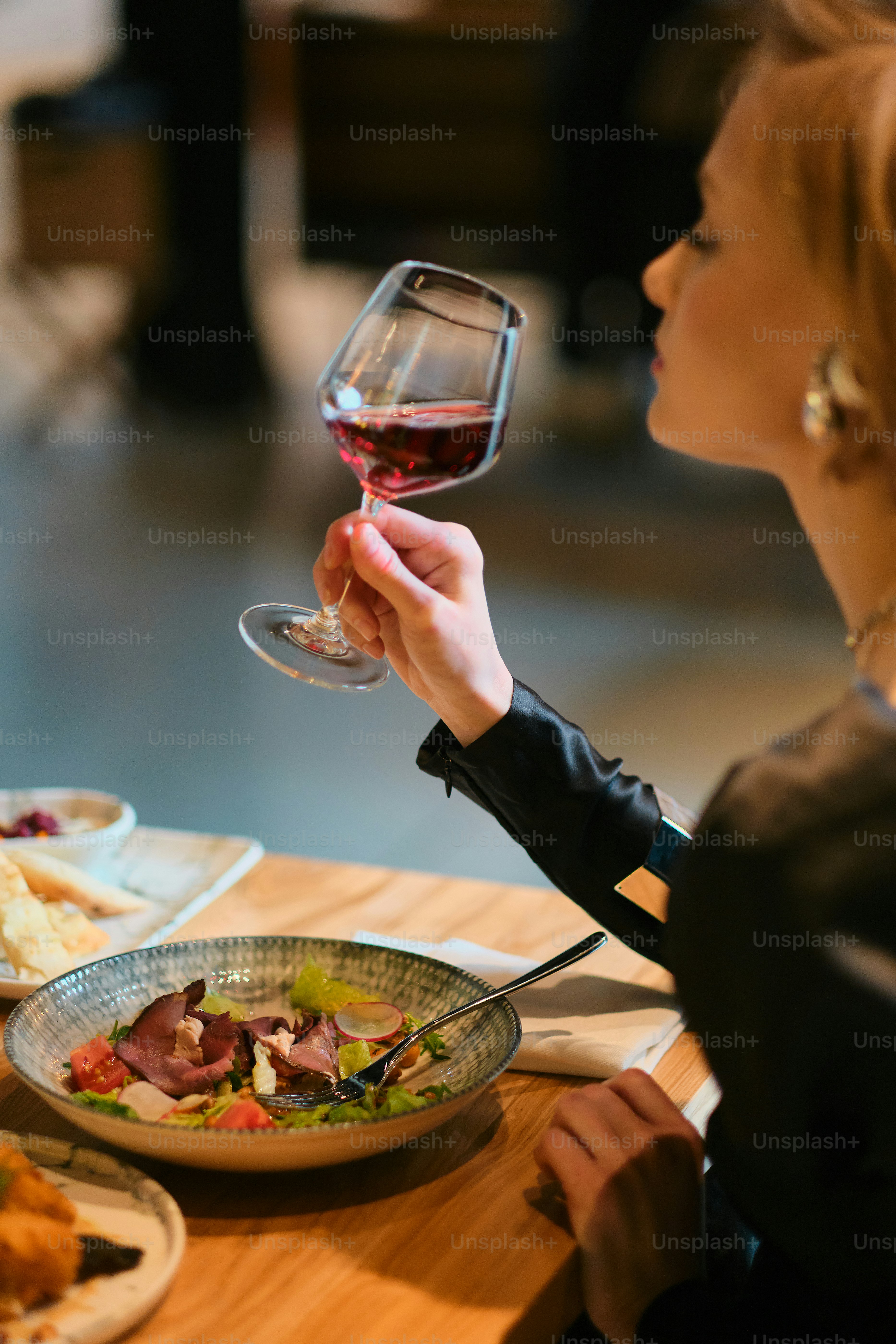 Woman enjoys wine and a meal at a restaurant.