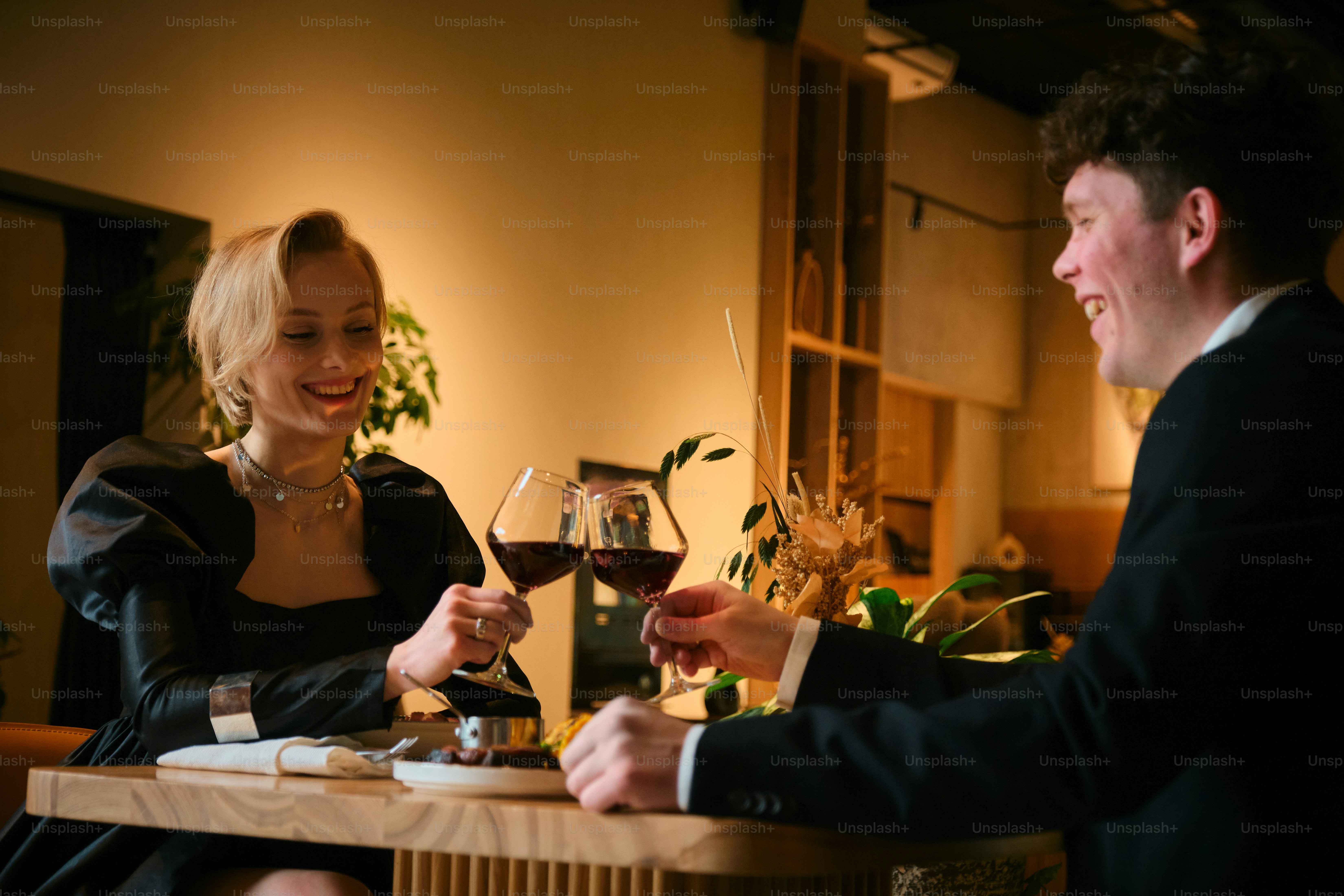 A couple cheers wine glasses during a date.