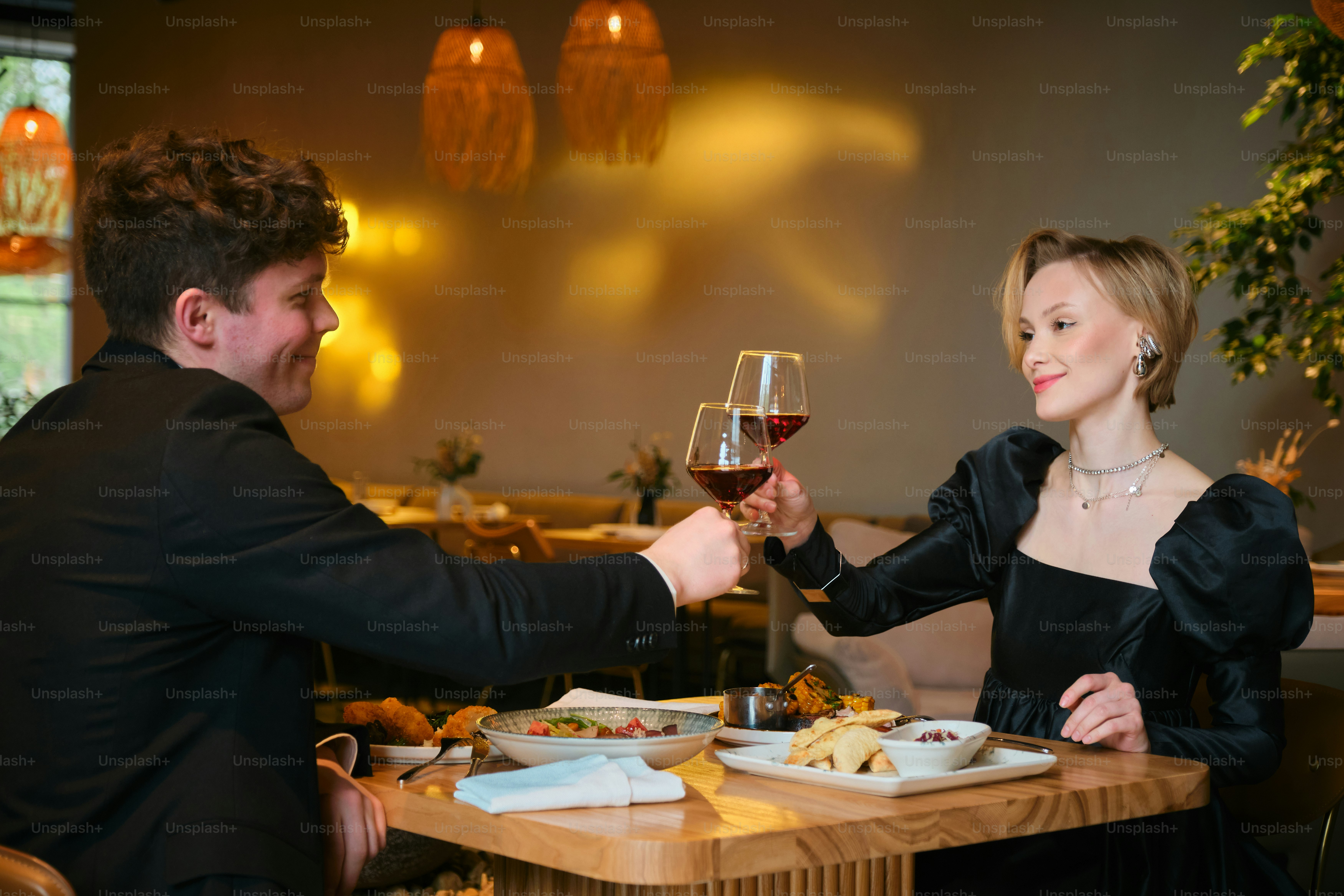 A couple toasts with wine at a restaurant.