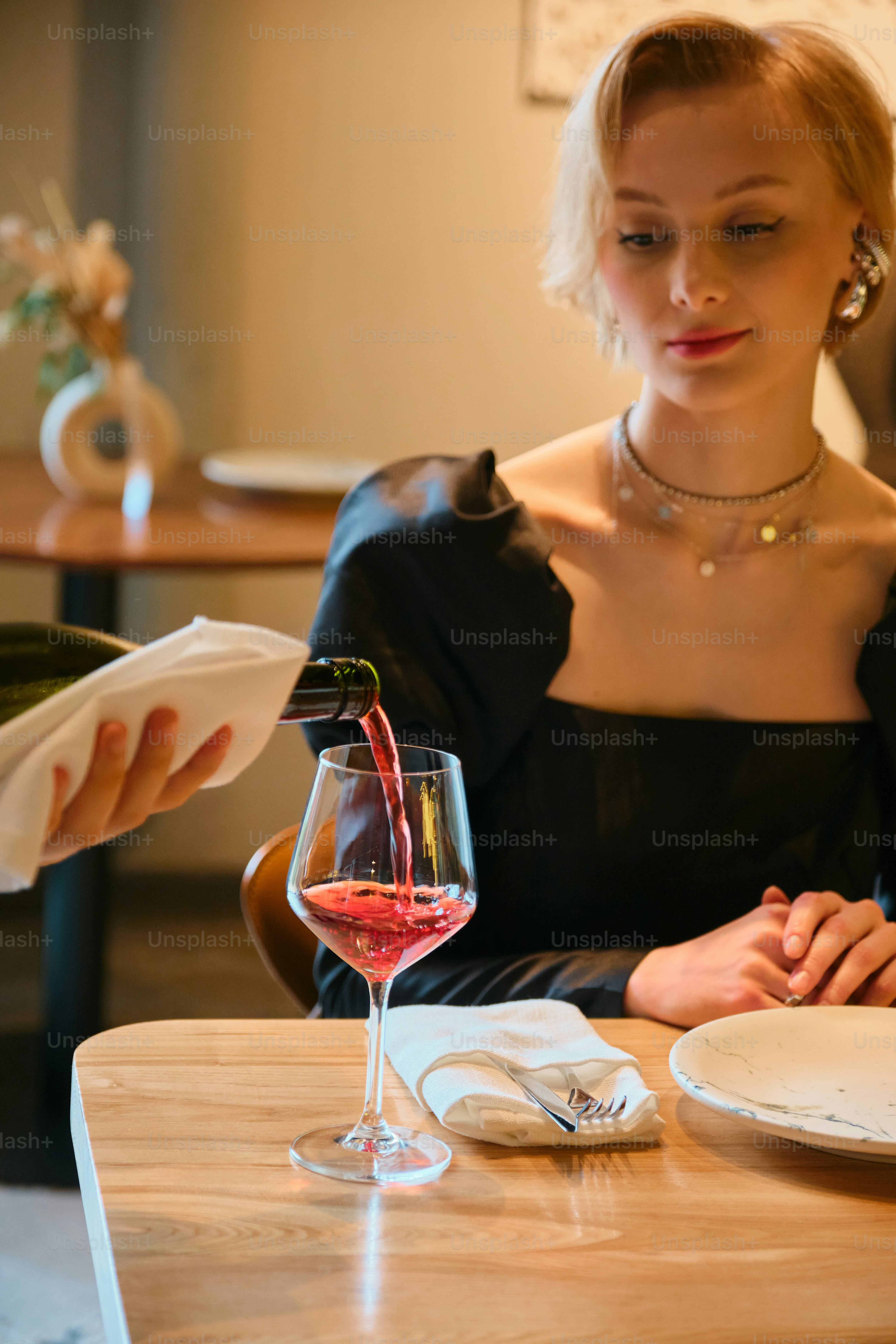 Wine is being poured for a woman at a restaurant.