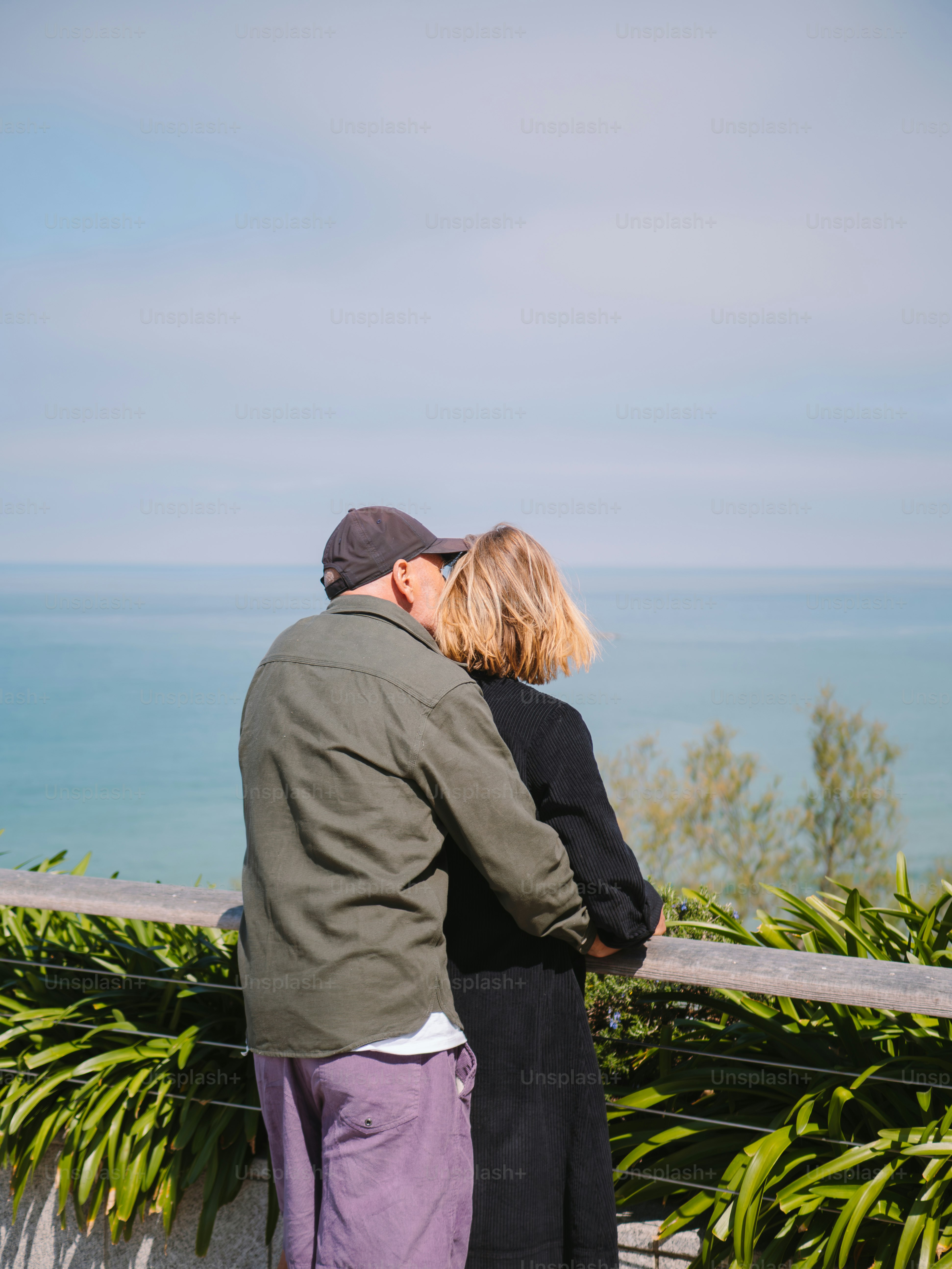 A couple embraces while looking at the ocean.