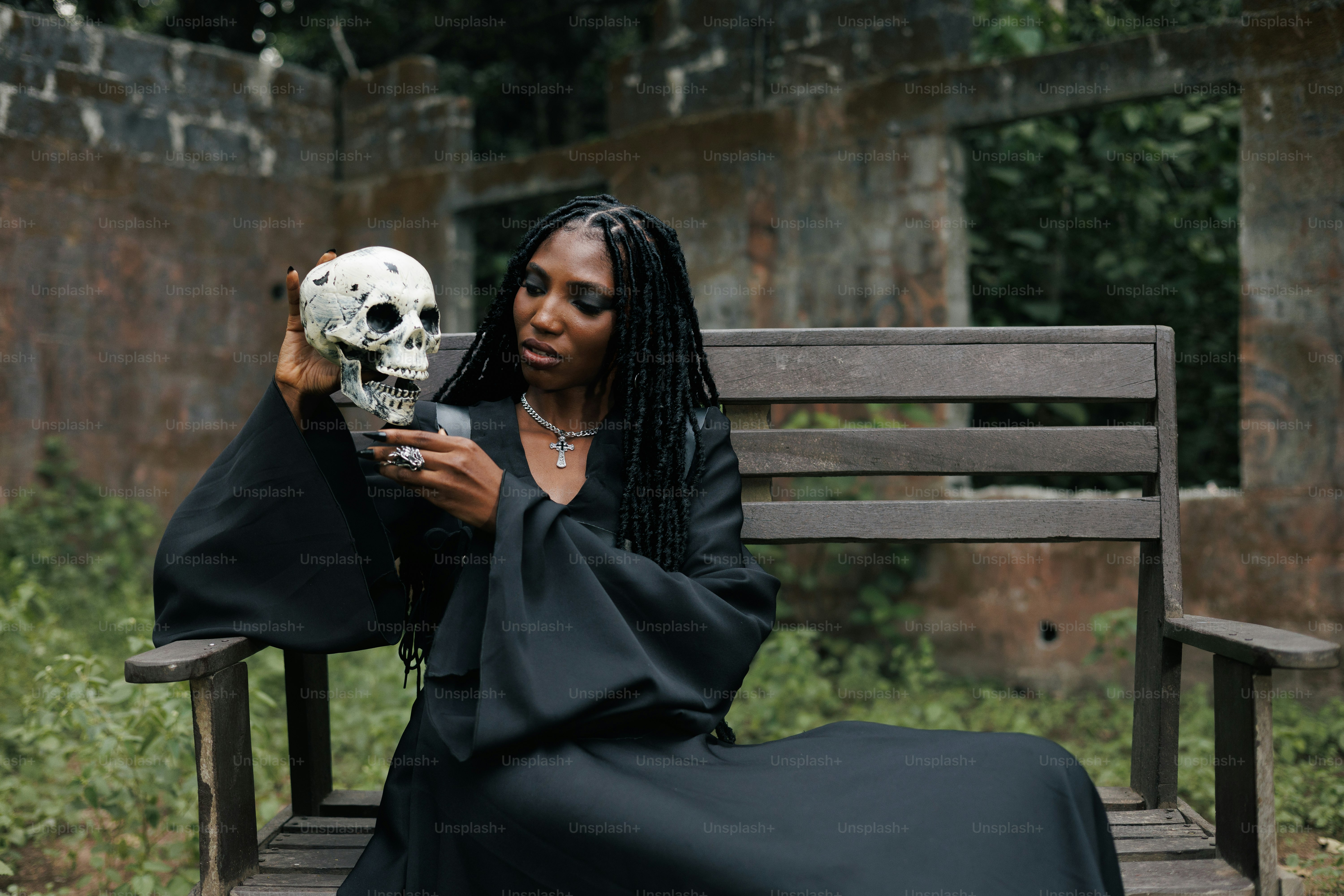 Woman holds a skull, sitting on a bench.