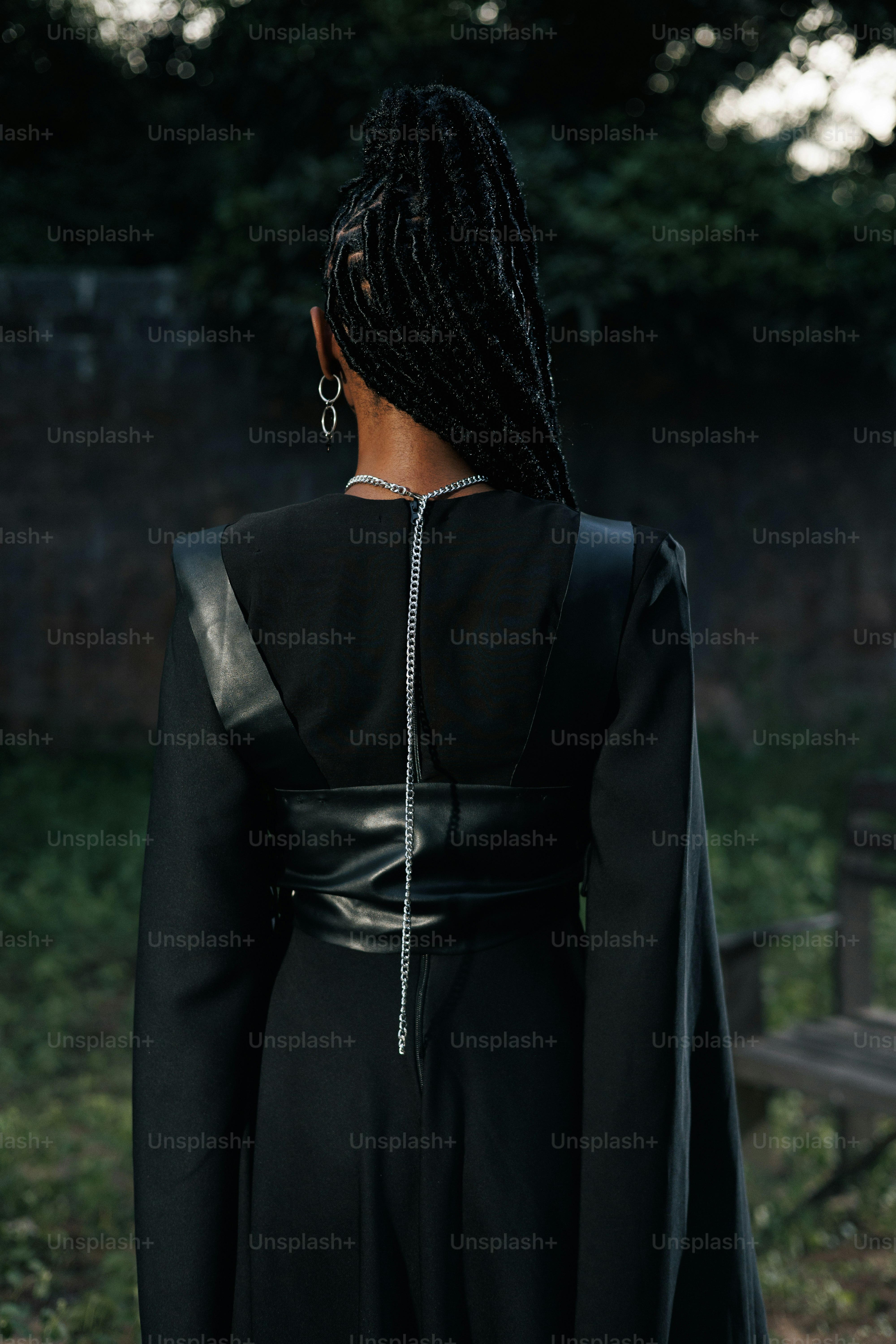 編みこみの髪とジュエリーを身に着けた黒いドレスを着た女性。