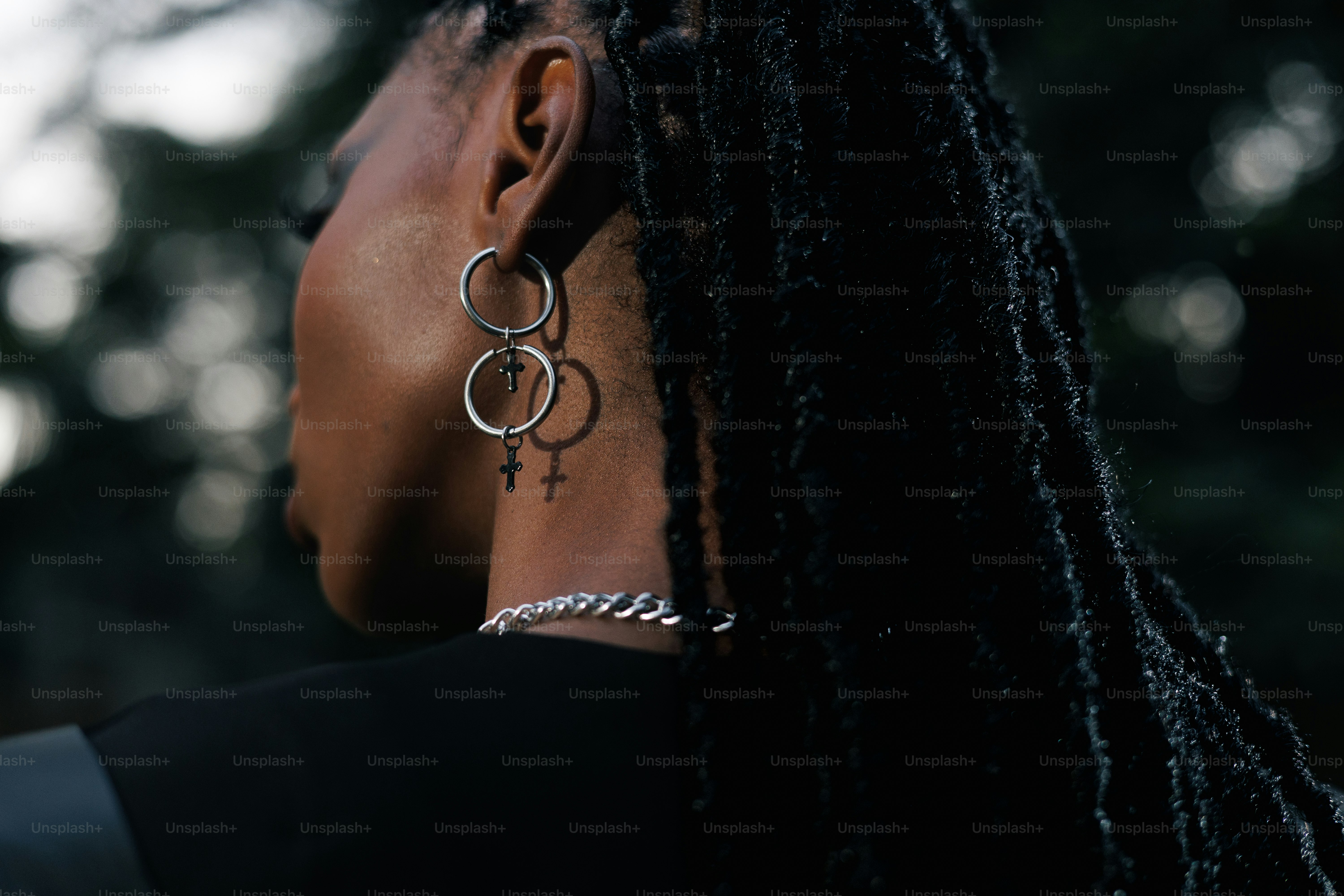 Woman with dreadlocks wears earrings and necklace.