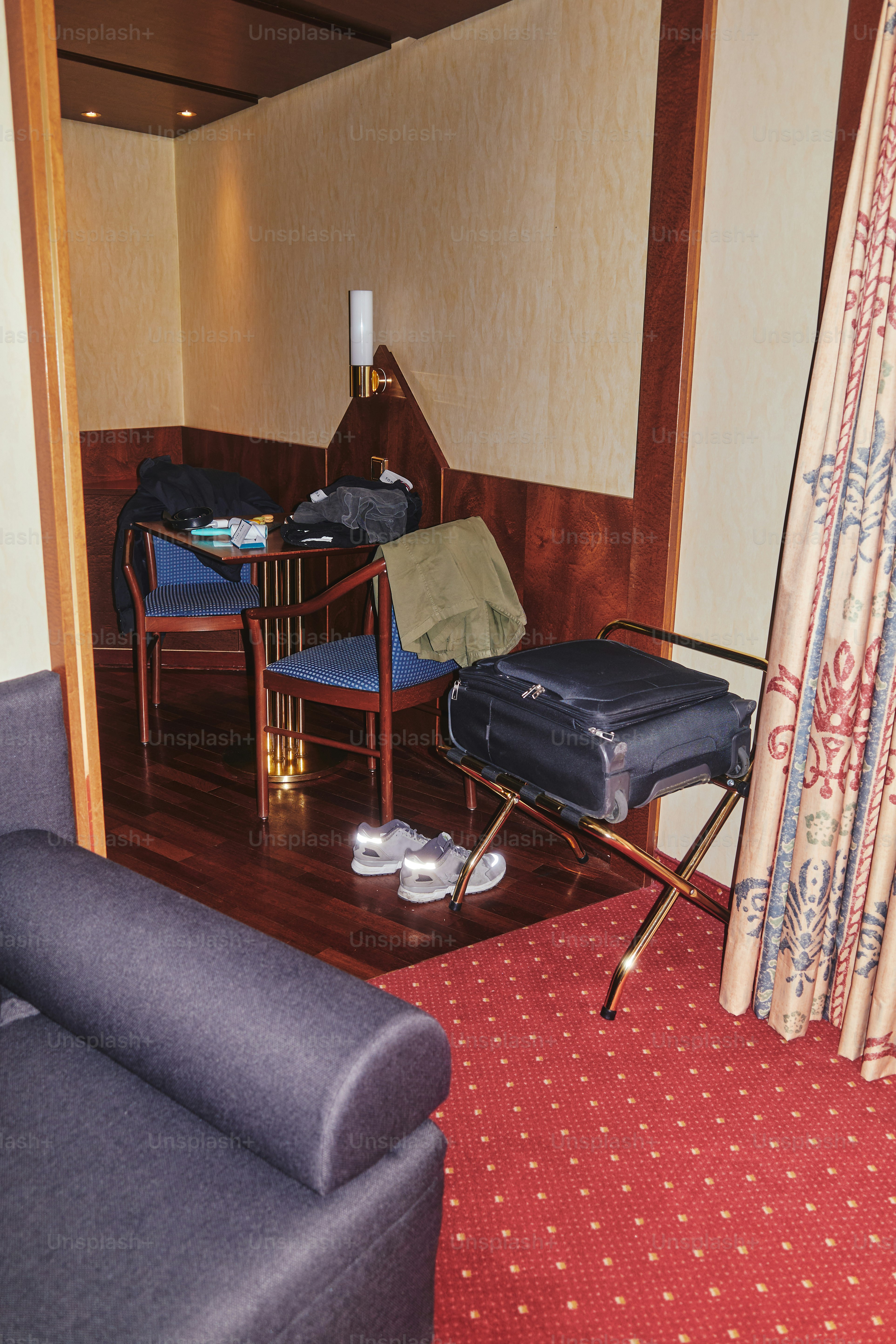 A hotel room with luggage and chairs.