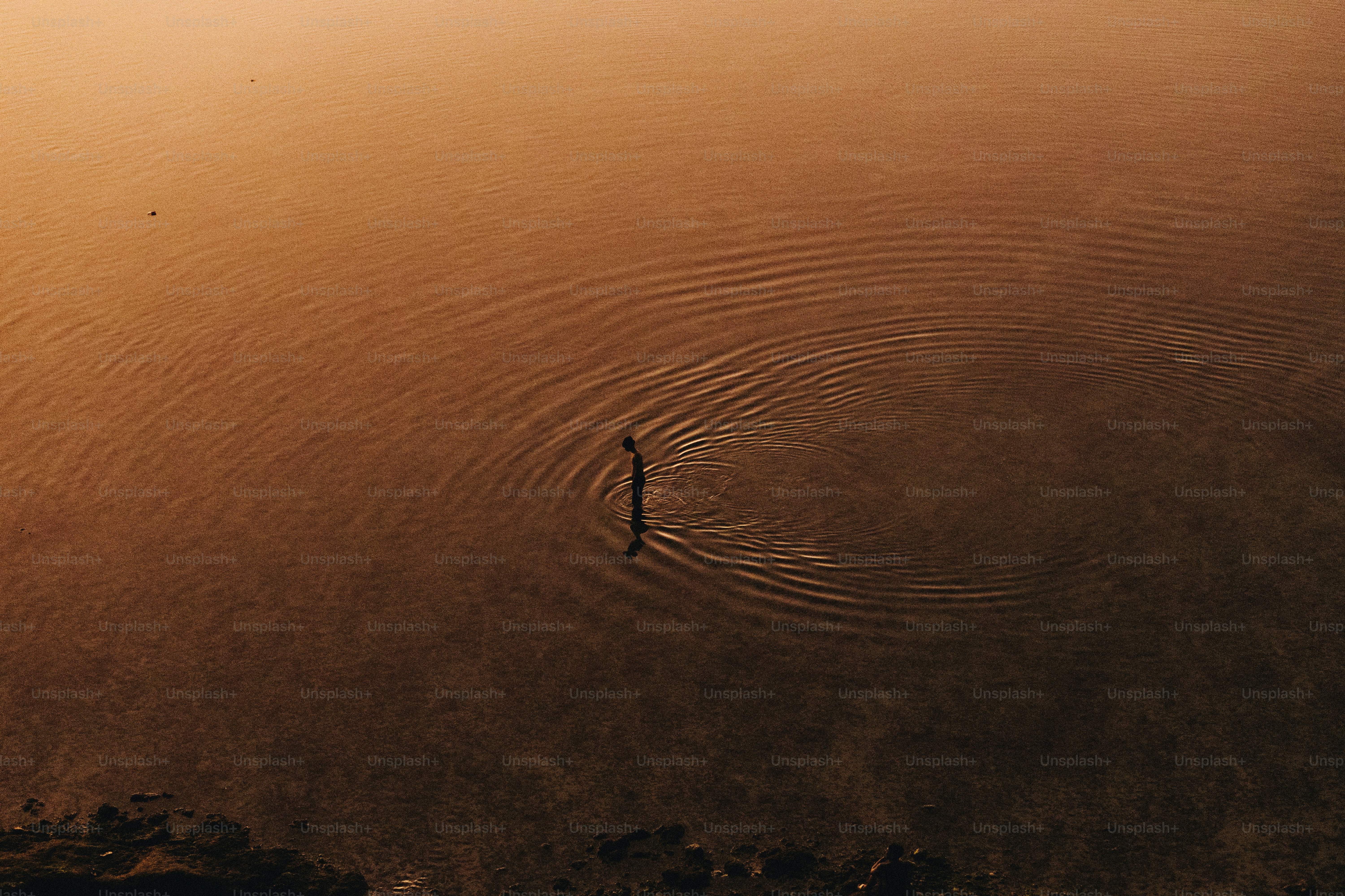 A person stands in water, creating ripples.
