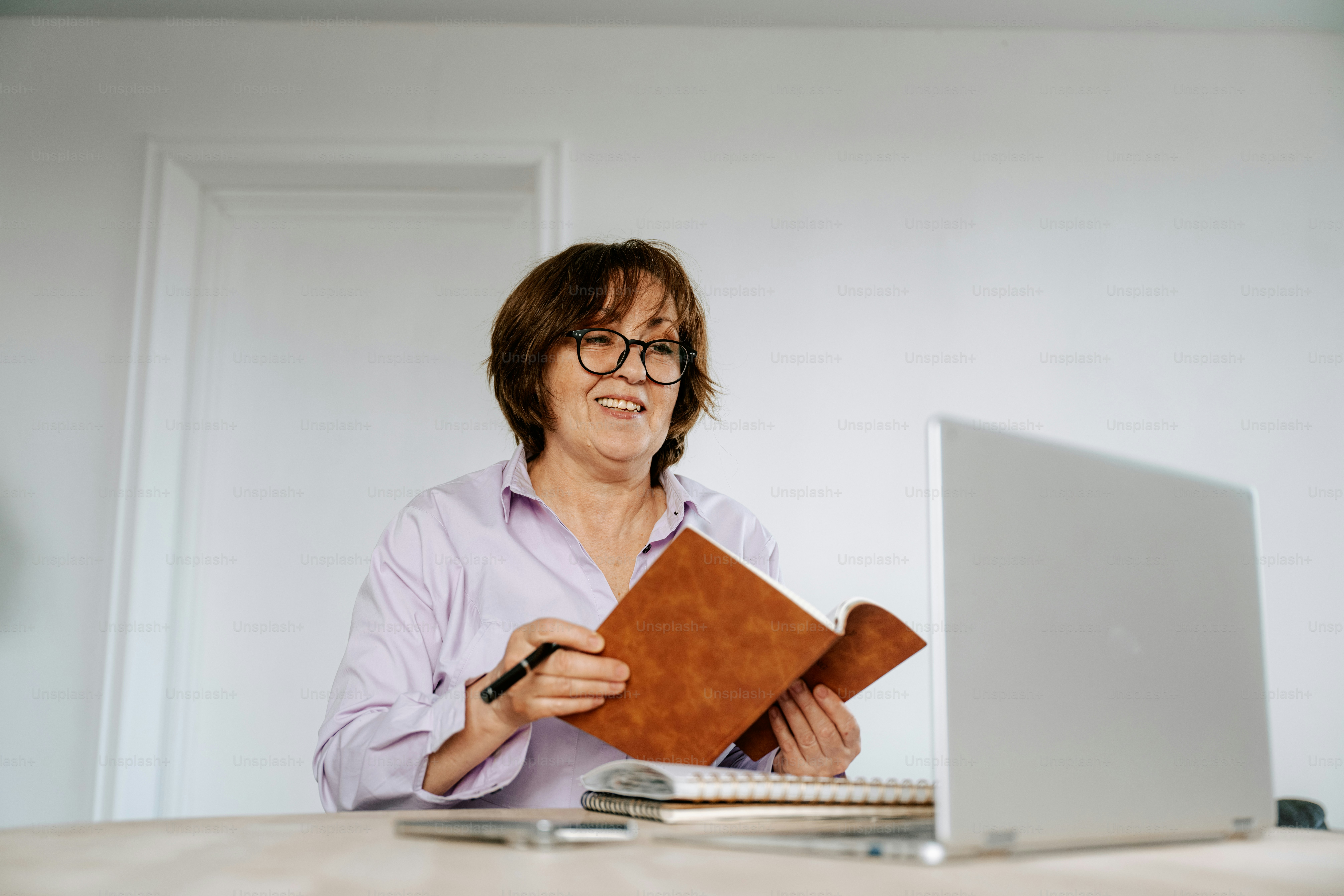 Woman works on a laptop and takes notes.