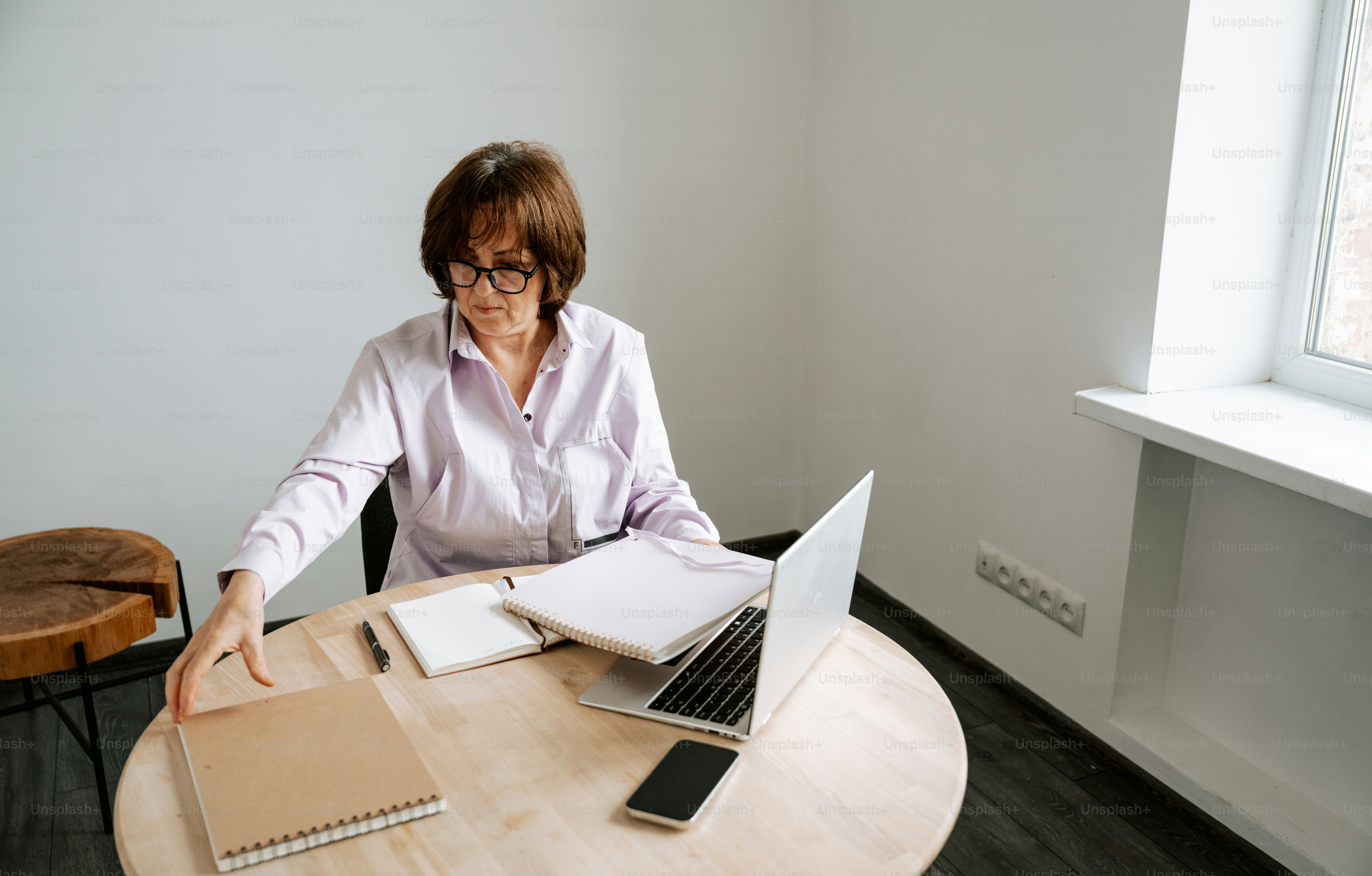 Woman works at a table with laptop and notebook.