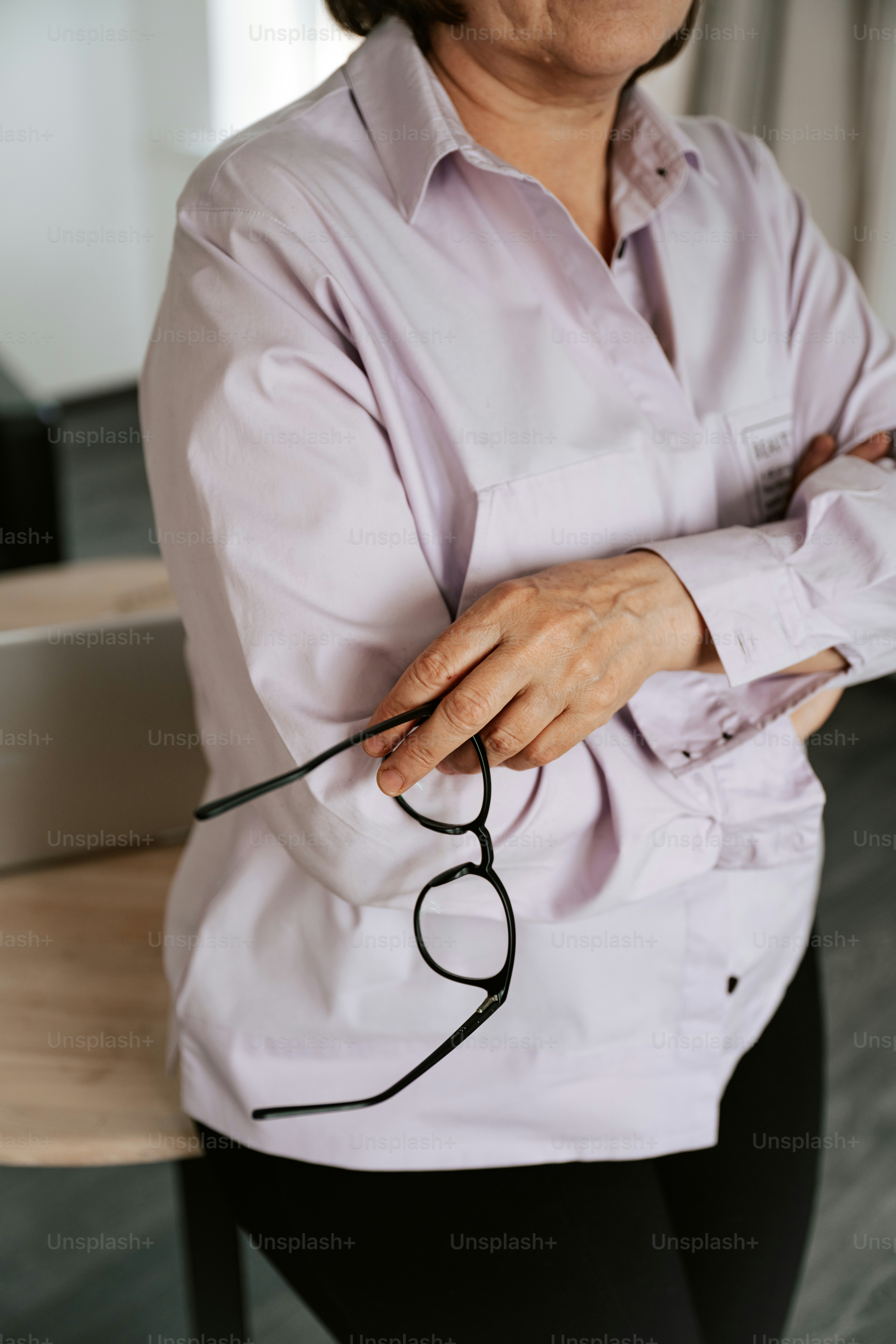 An older woman holds eyeglasses.