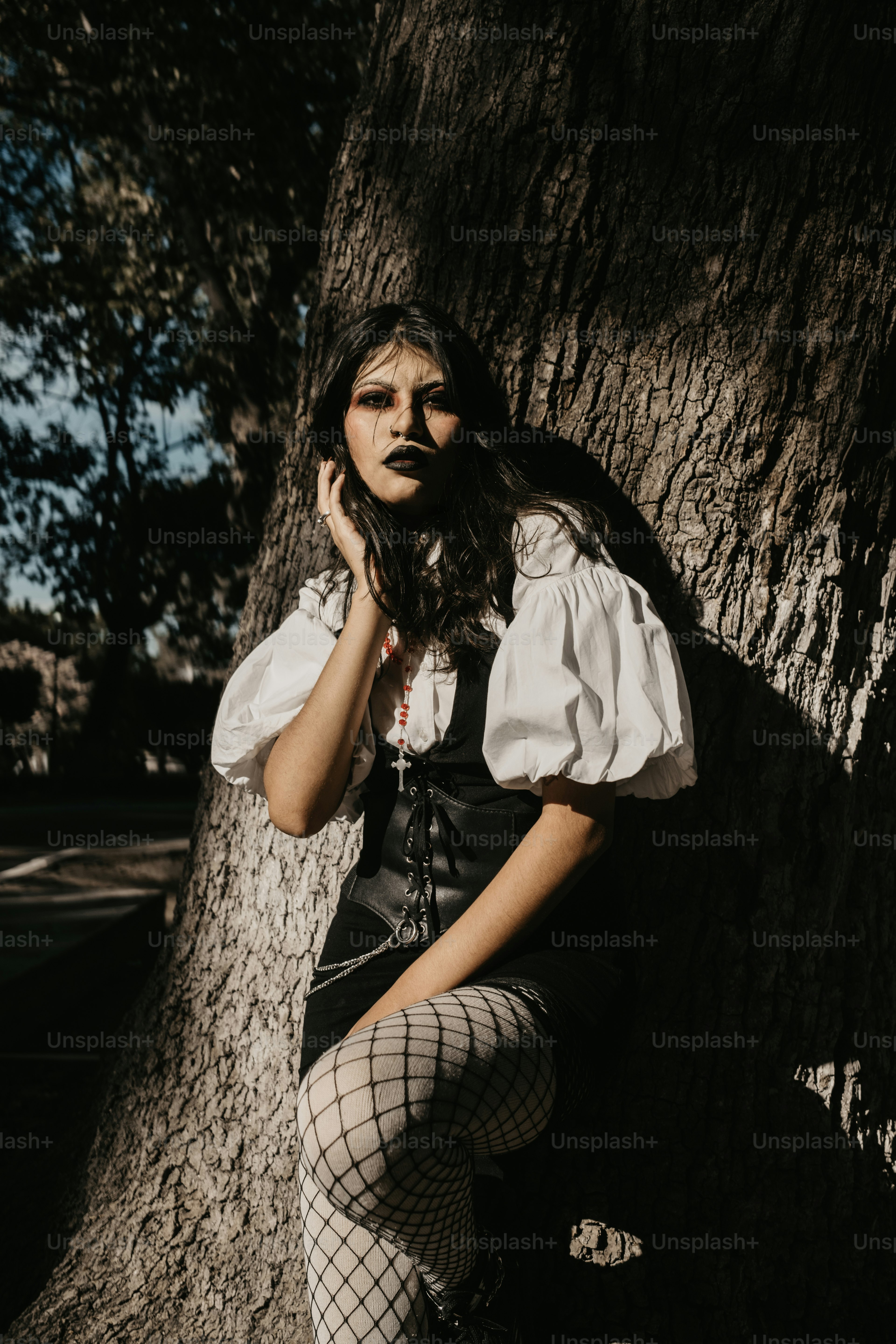 A gothic woman poses behind tree roots. photo – Fashion Image on Unsplash