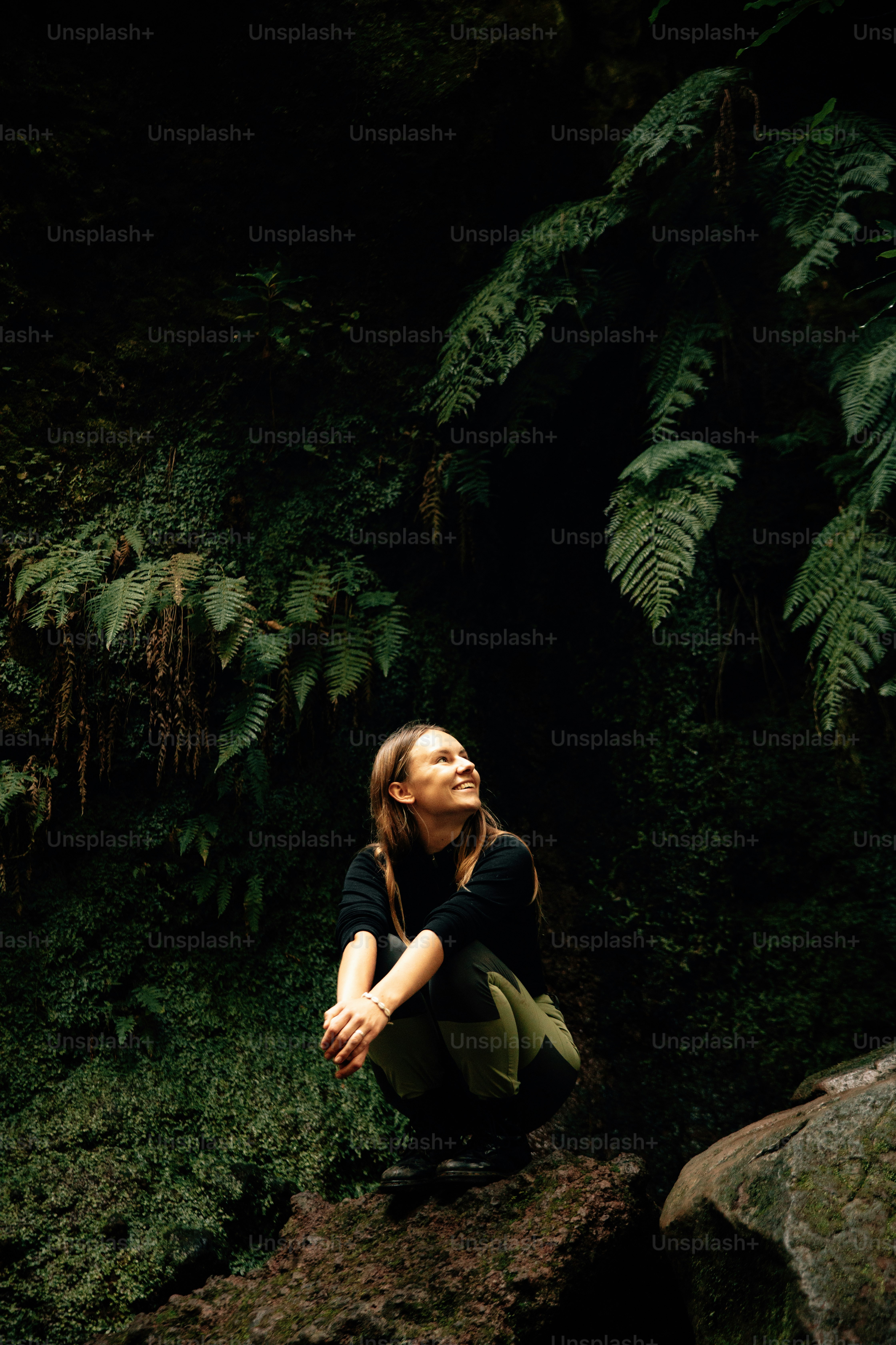 Woman gazes upwards in a lush, green forest.