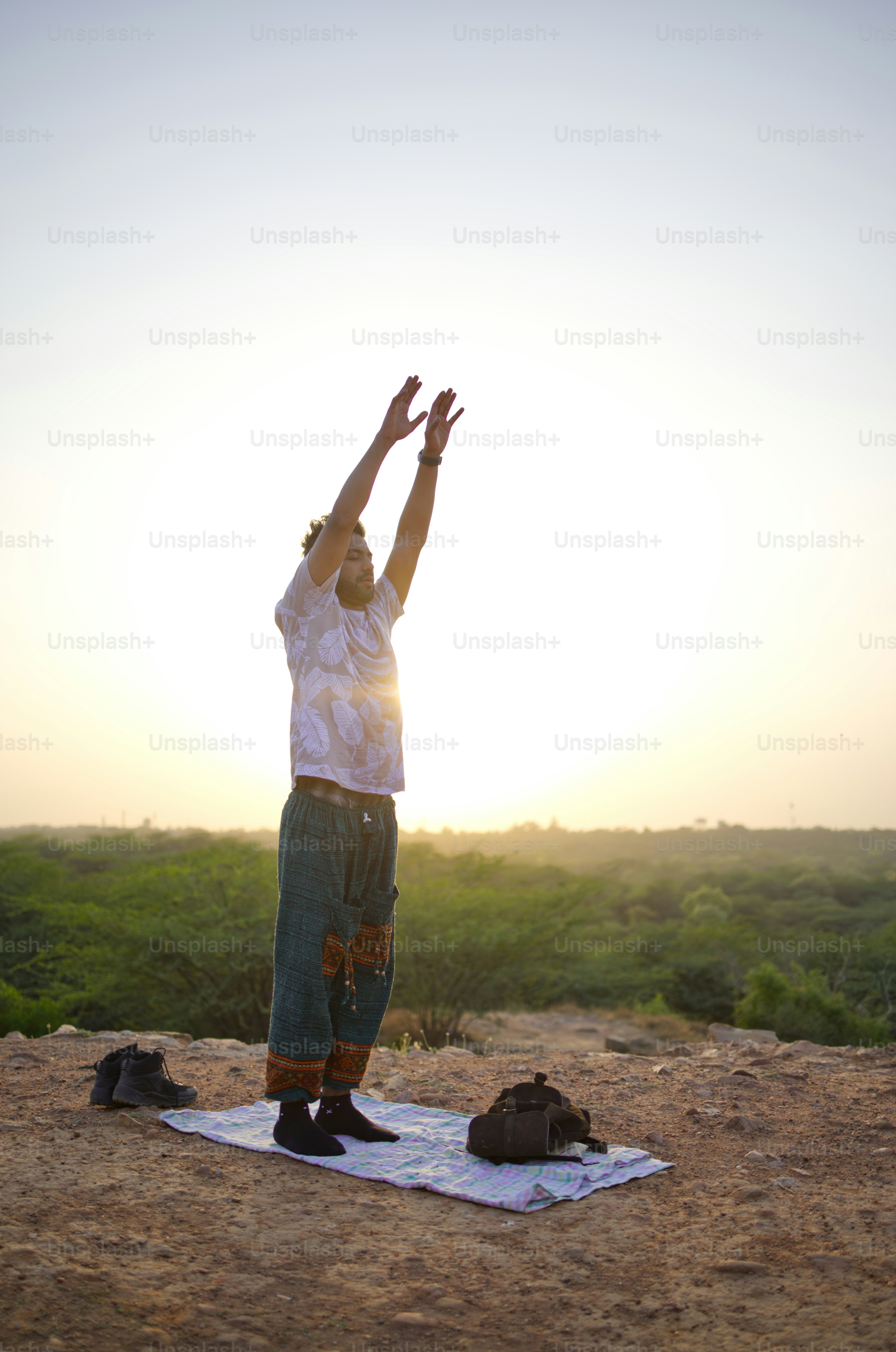 Man does yoga outdoors at sunrise.