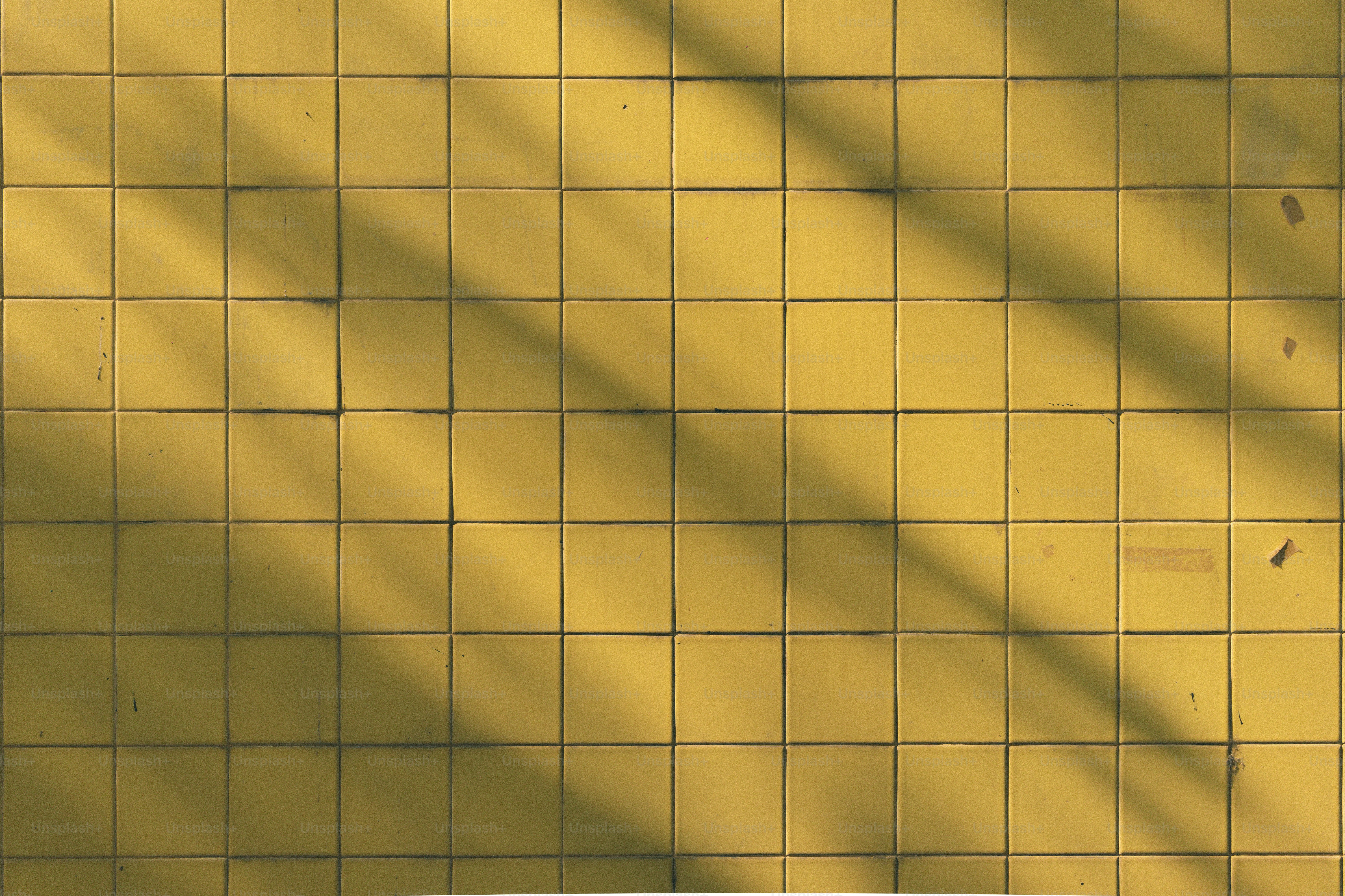 Yellow tiles with shadows cast across.
