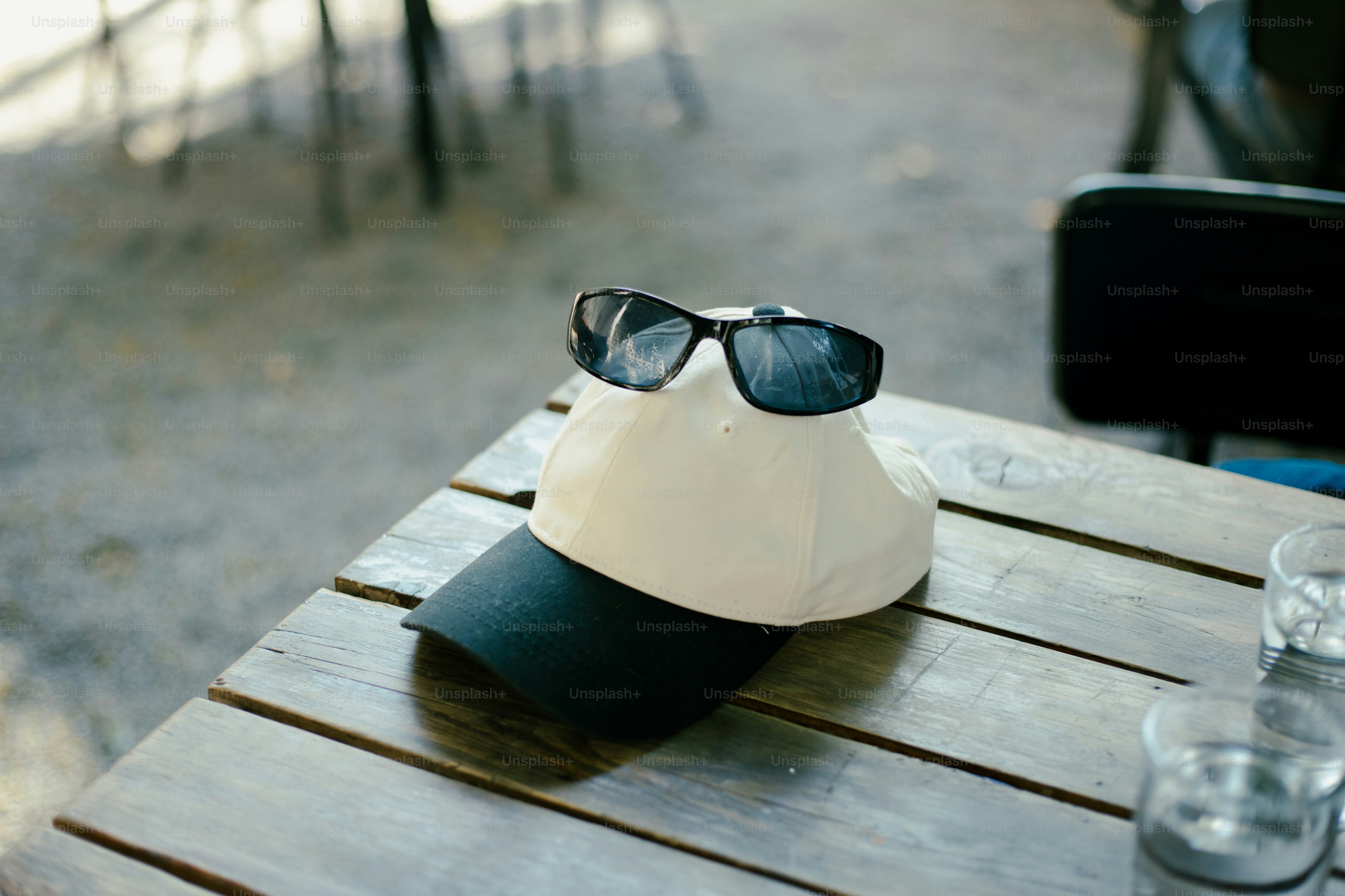 Sunglasses rest on a cap on a table.