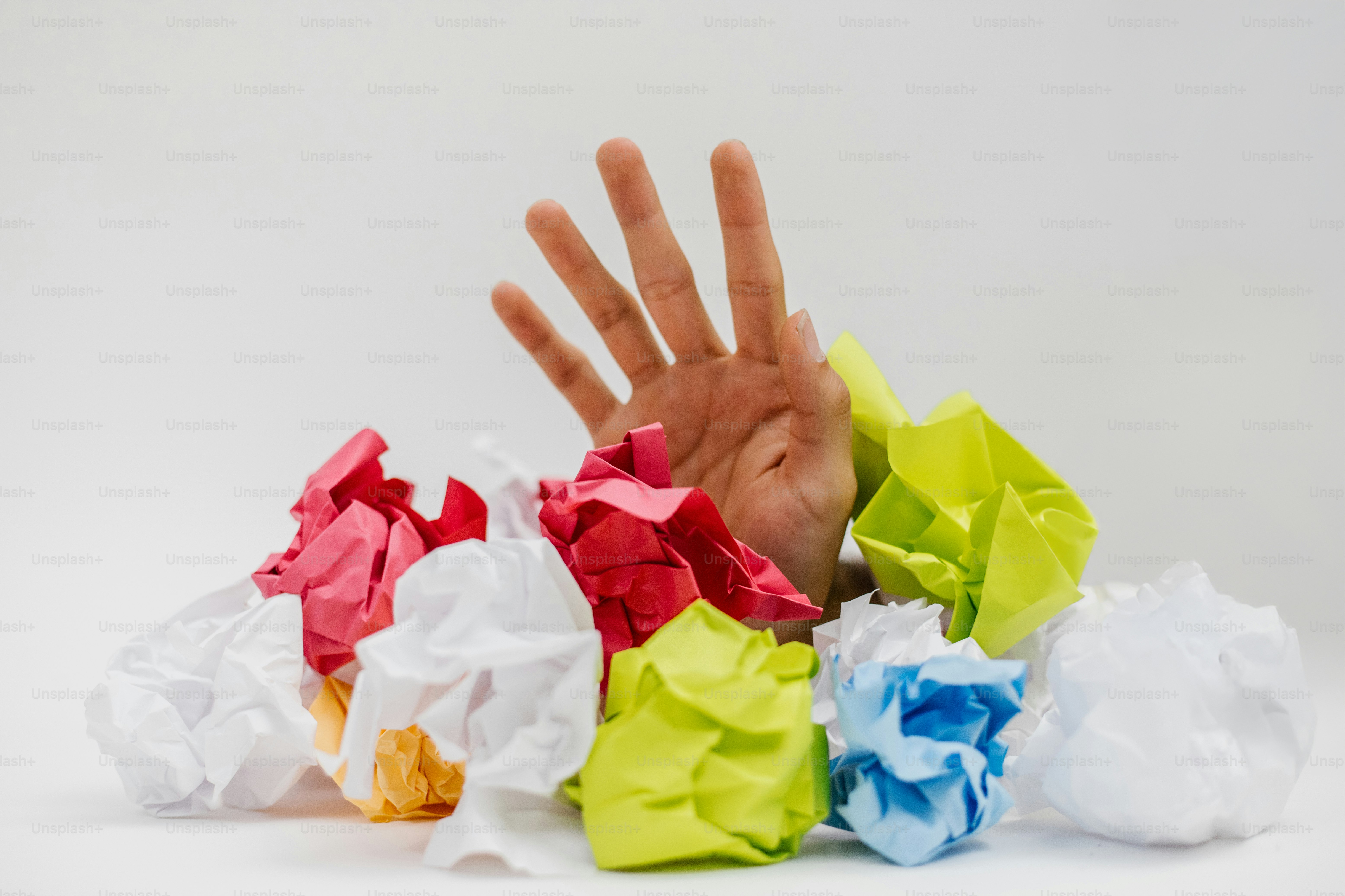 A mão emerge do papel amassado colorido.