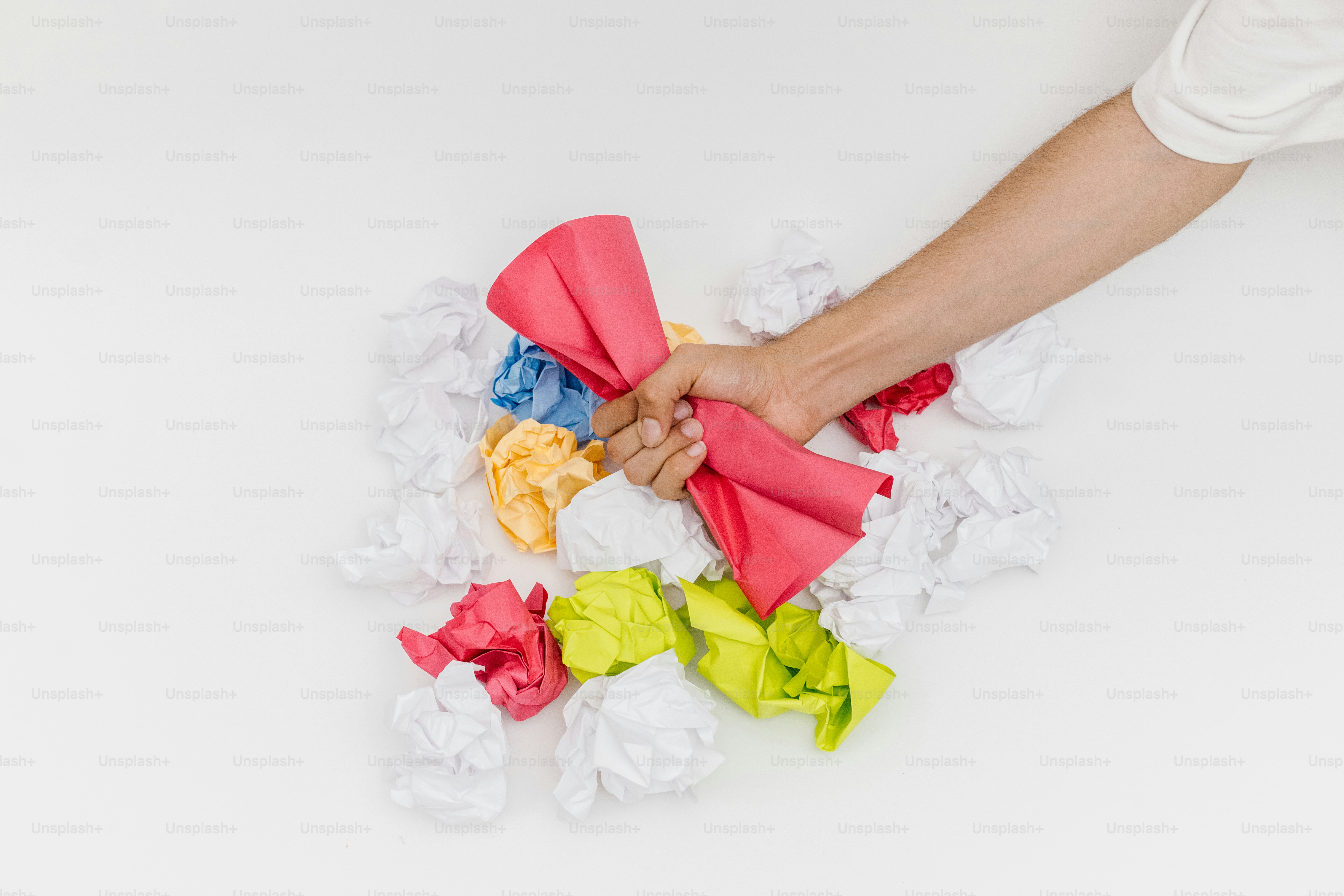 Mão esmaga papel amassado, mostrando frustração.