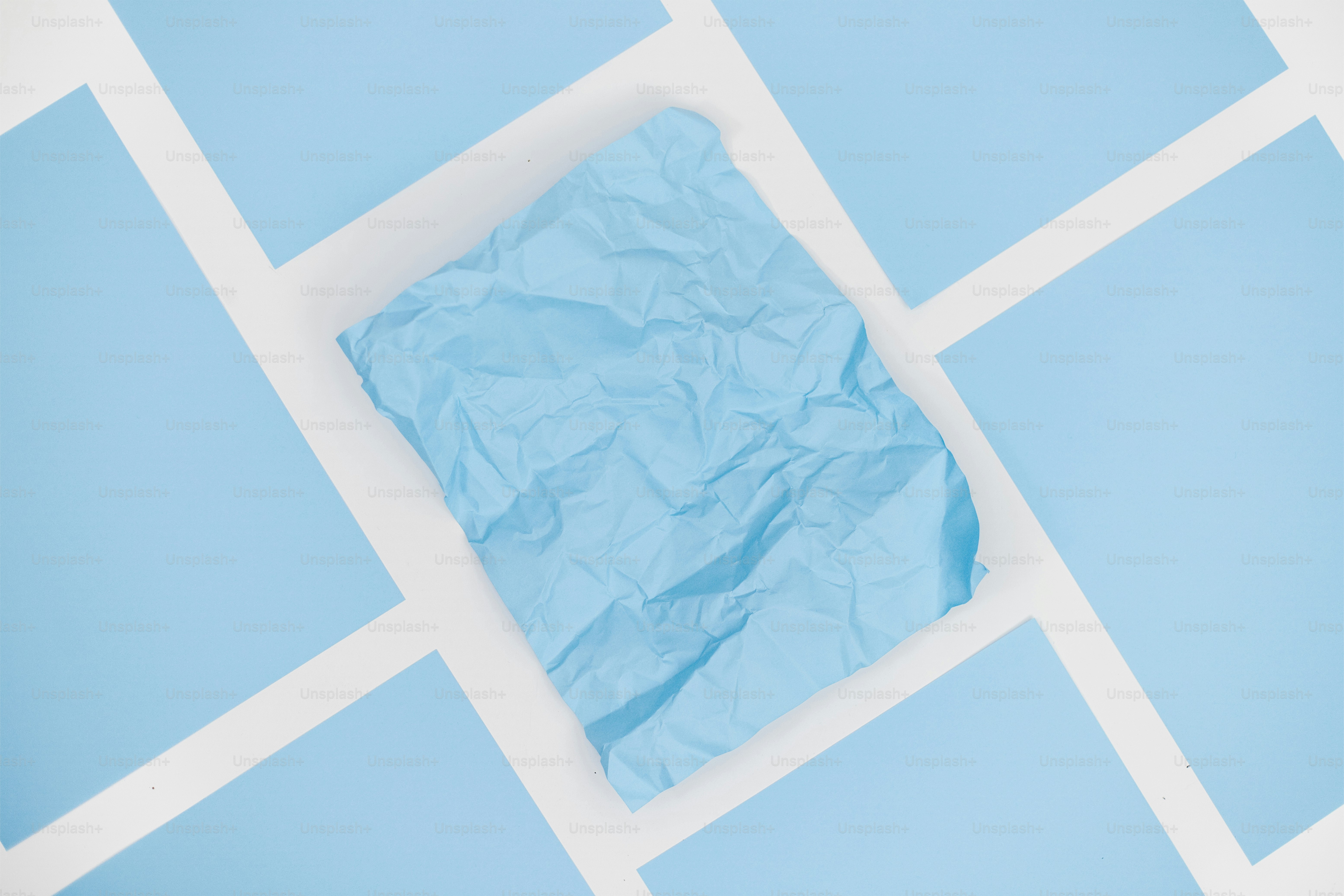 Un papel arrugado rodeado de papeles azules planos.