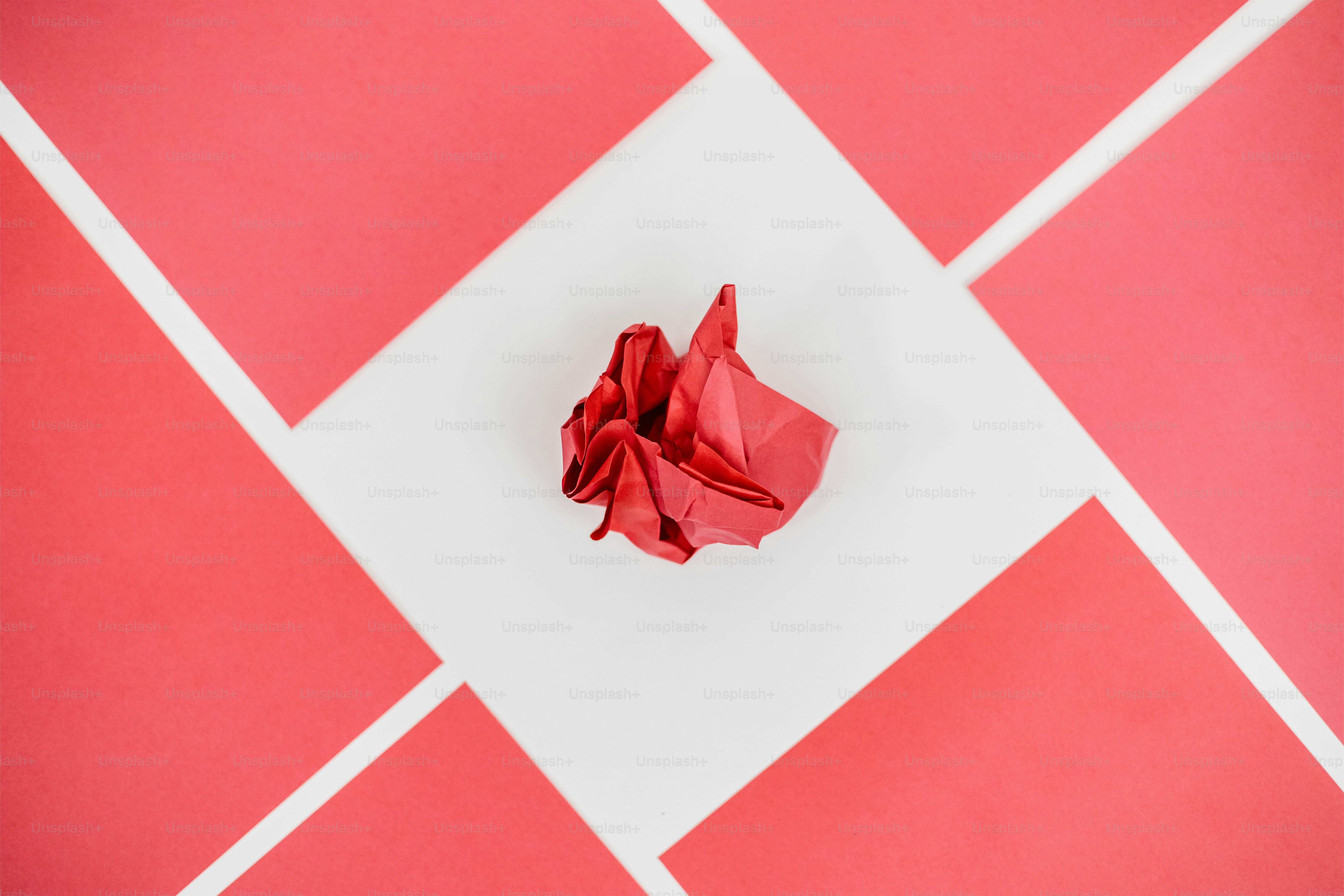 A red, crumpled paper heart in a white square.