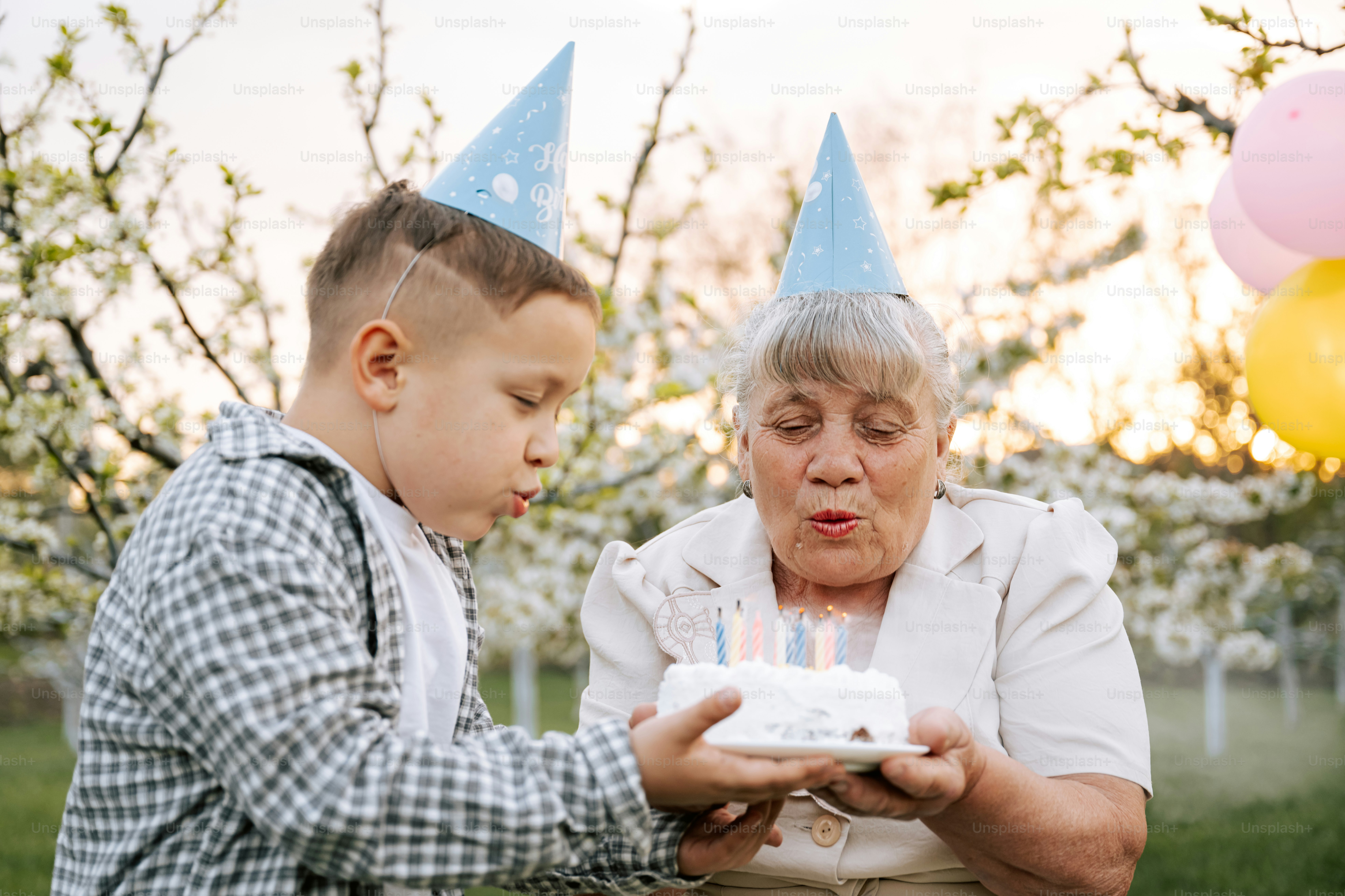 Der Enkel hilft der Oma beim Ausblasen der Geburtstagskerzen.