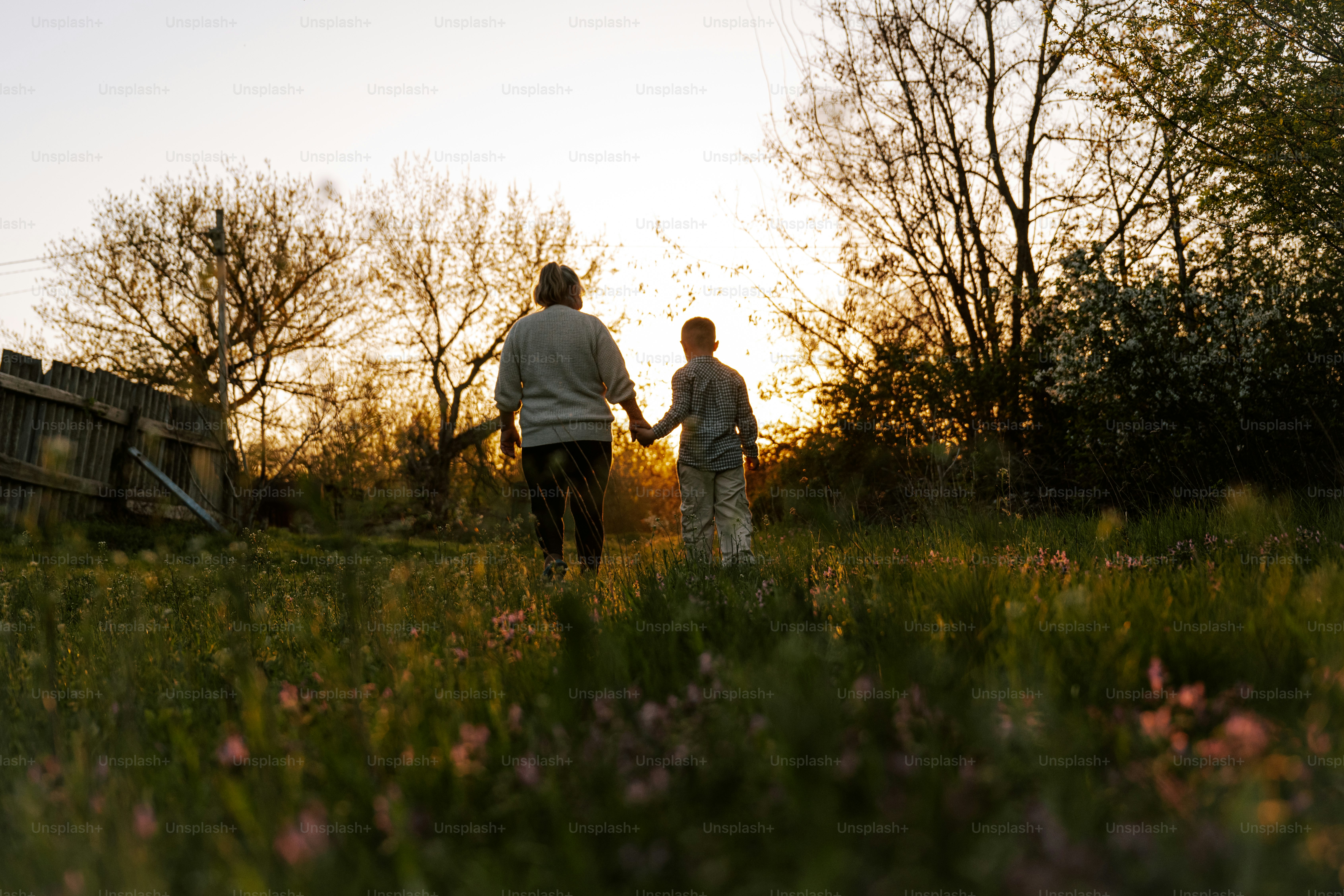 Eine Person und ein Kind gehen in den Sonnenuntergang.