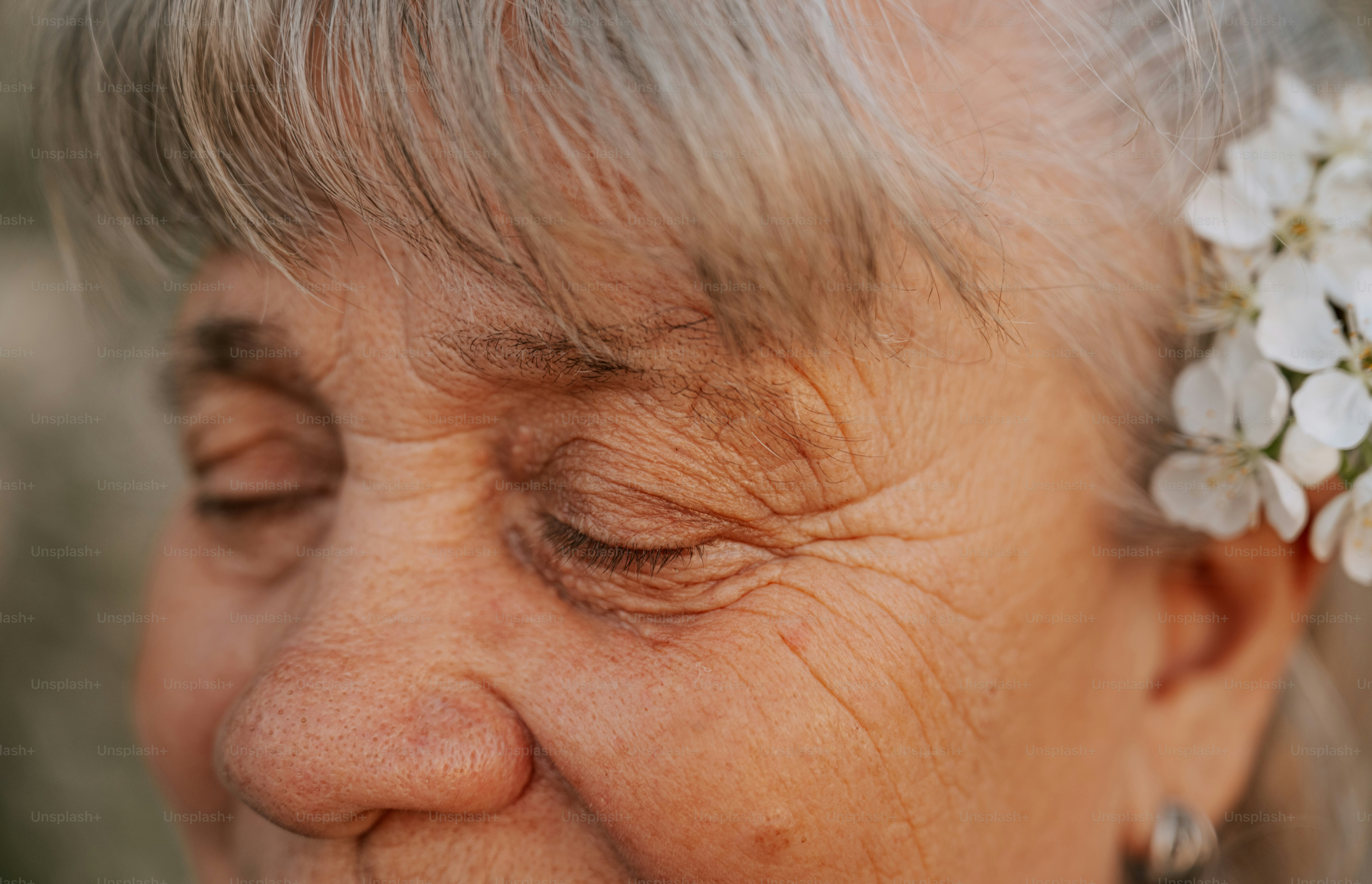 An elderly woman with closed eyes and wrinkles.